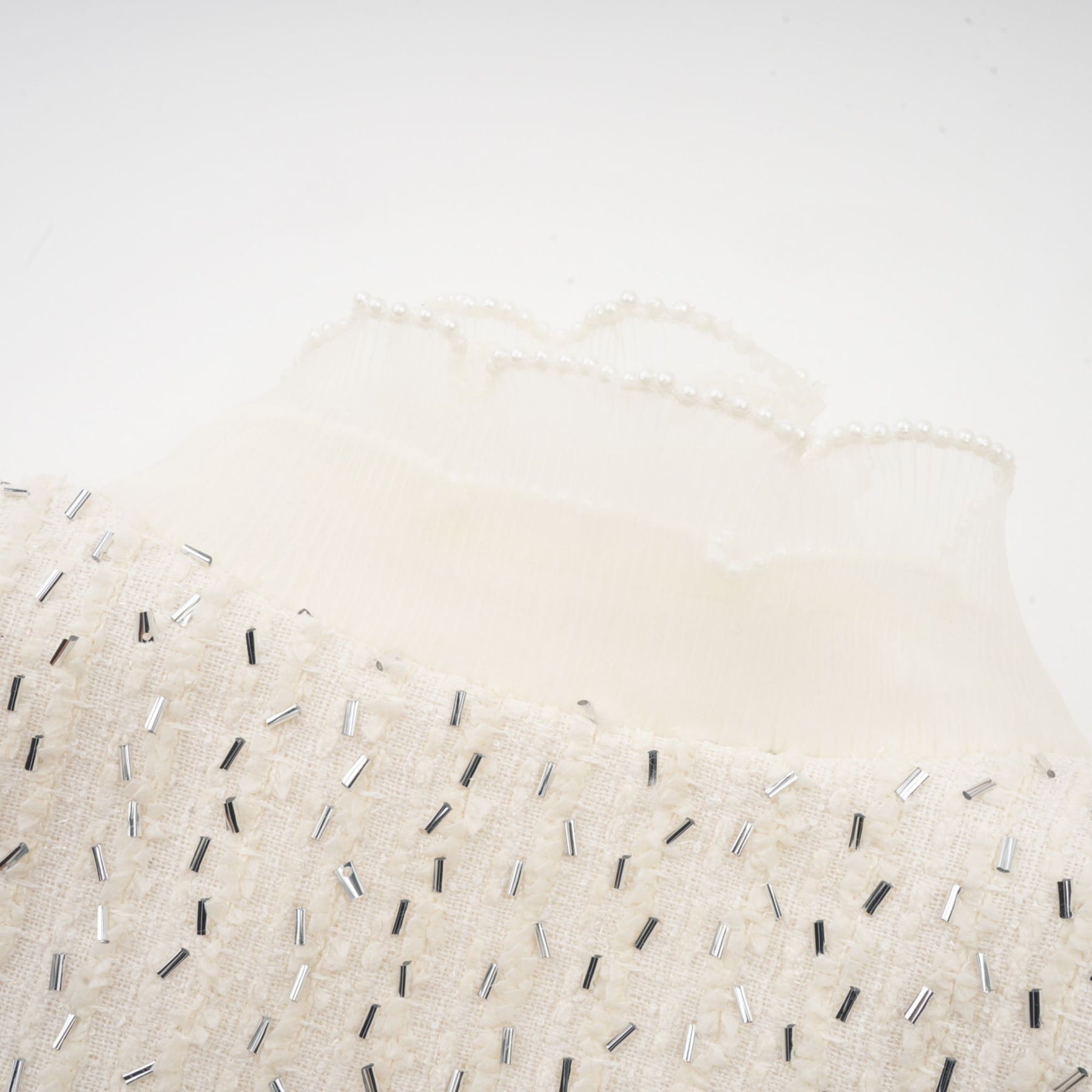 A cropped white jacket with beaded embellishments and ruffle details named Blanche