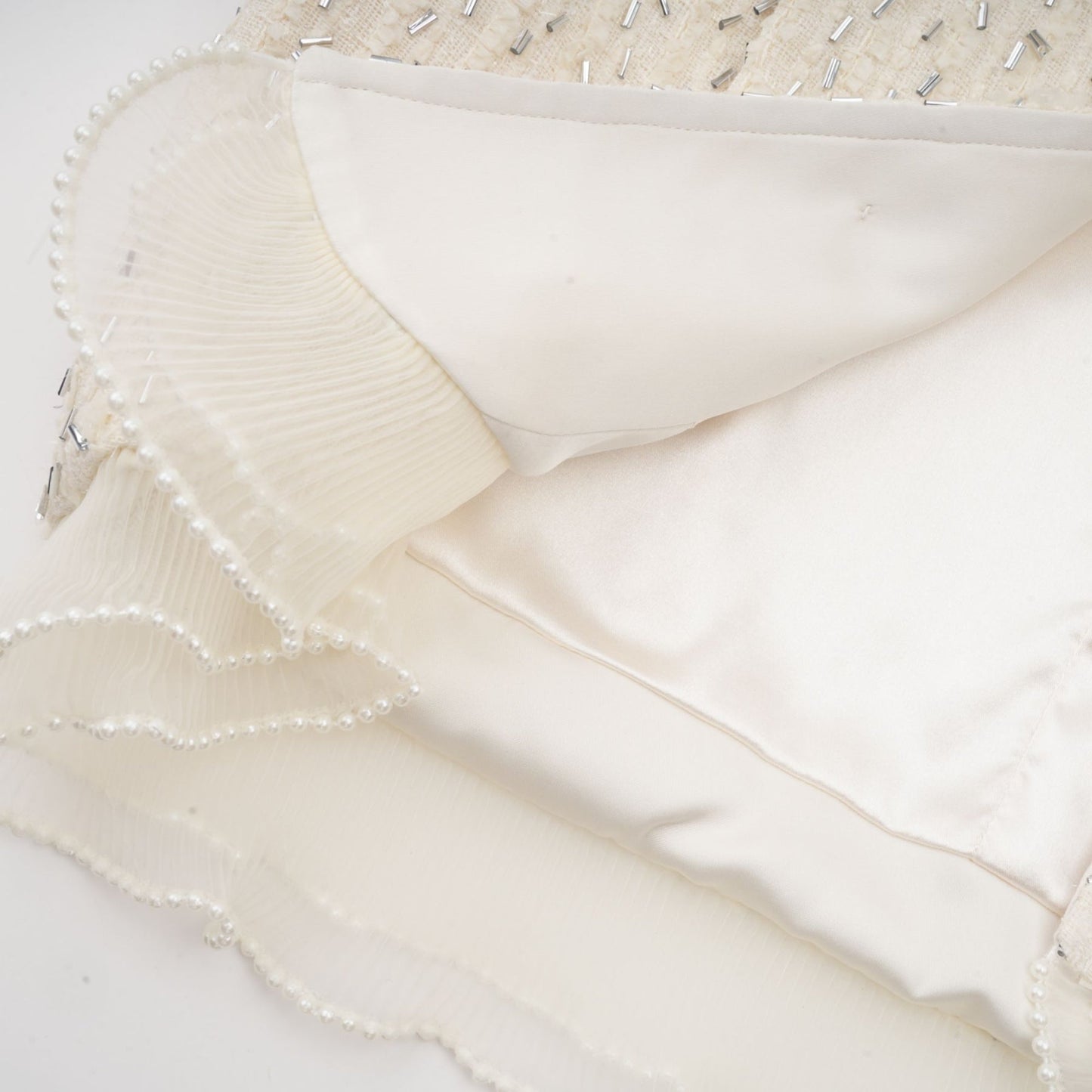 A cropped white jacket with beaded embellishments and ruffled details named Blanche