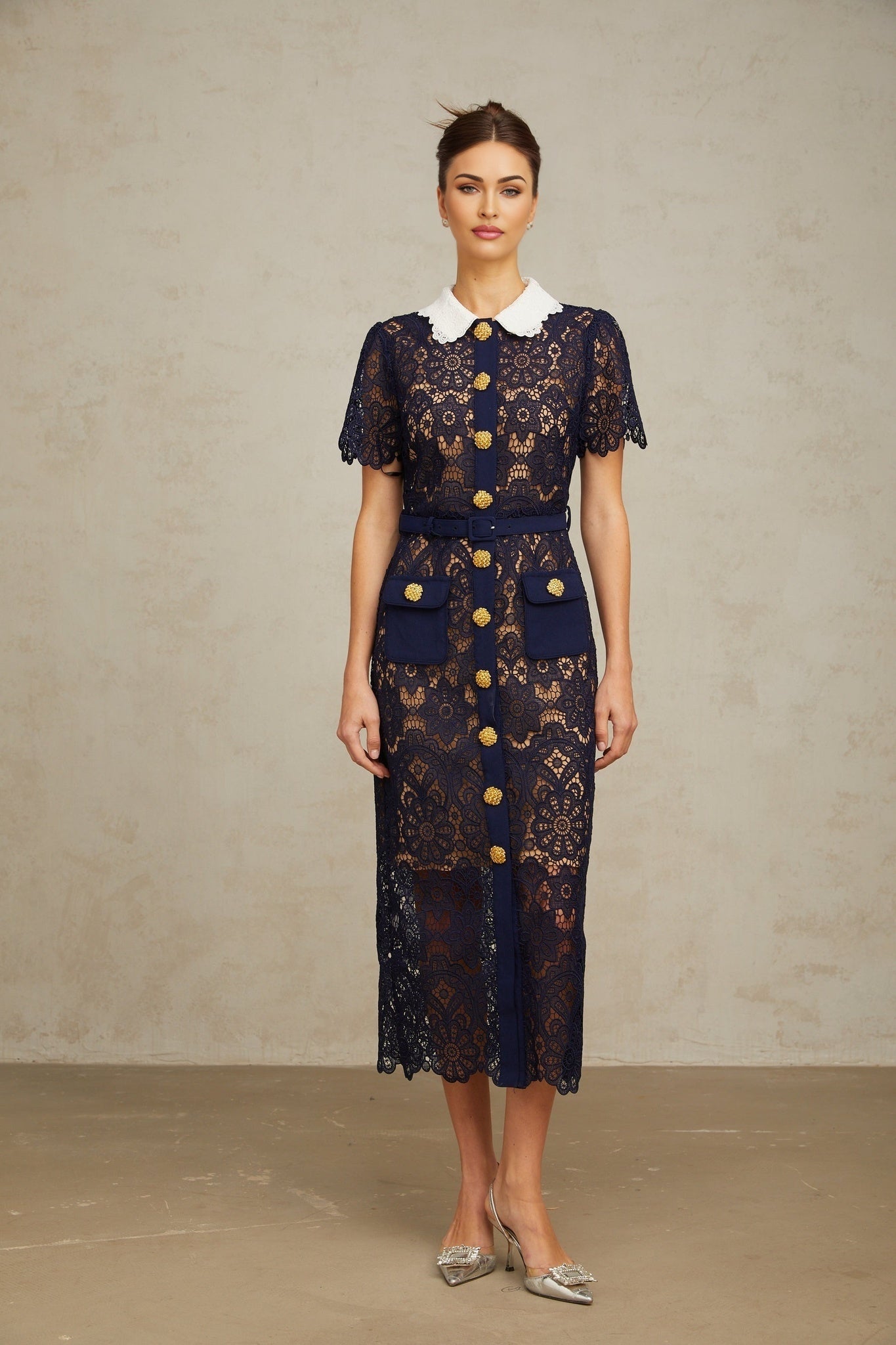 A dark blue midi dress with floral crochet lace patterns covering the entire garment The dress features a fitted silhouette and delicate lace detailing throughout