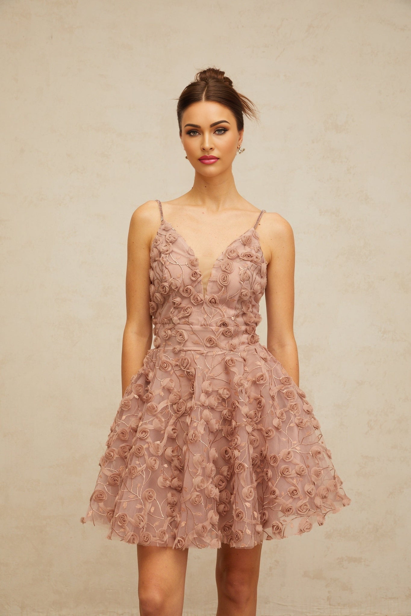 A dusty pink mini dress with flounced hem featuring rose appliqués and a feminine silhouette