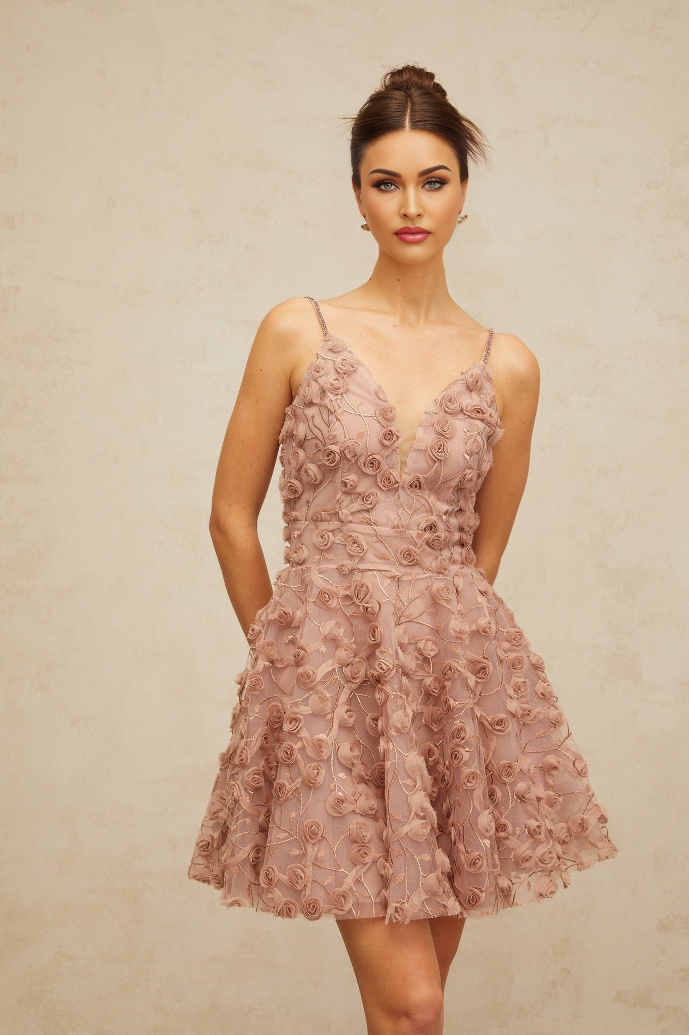 A dusty pink mini dress with rose appliques and a flounced hem featuring a feminine and romantic design