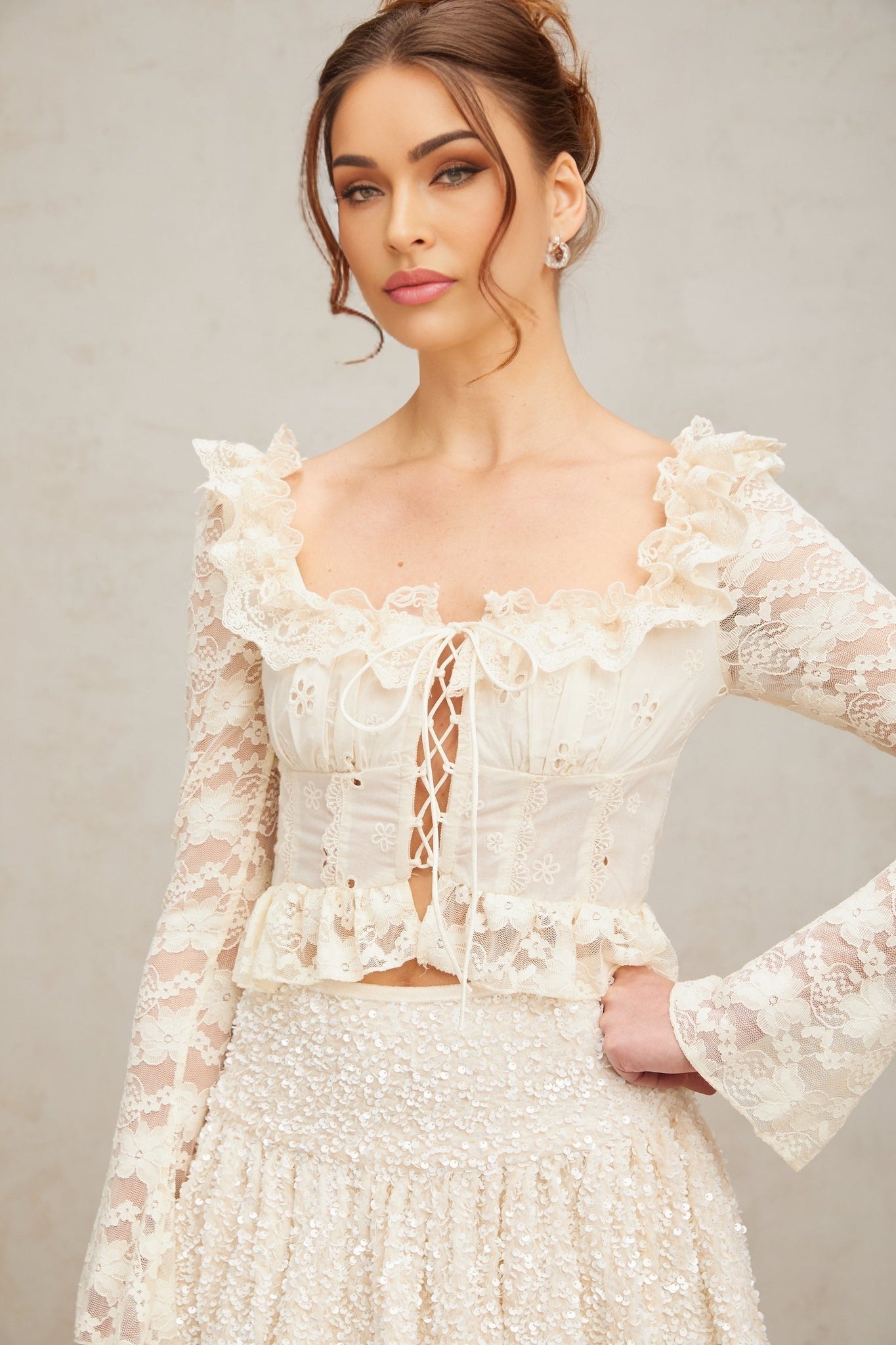 A feminine off white blouse with delicate floral lace pattern and ruffled details