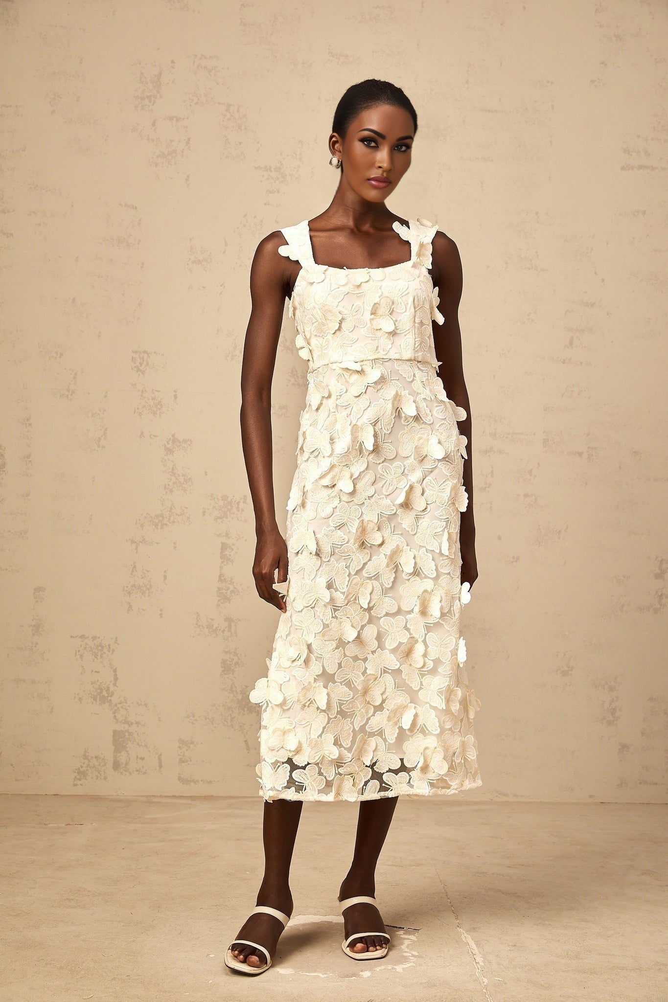 A flared midi dress with butterfly appliques adorning the fabric The dress features a fitted bodice and flowing skirt that flares out at the waist The butterflies appear to be delicately attached creating a whimsical and feminine design The overall style is elegant and romantic suitable for special occasions