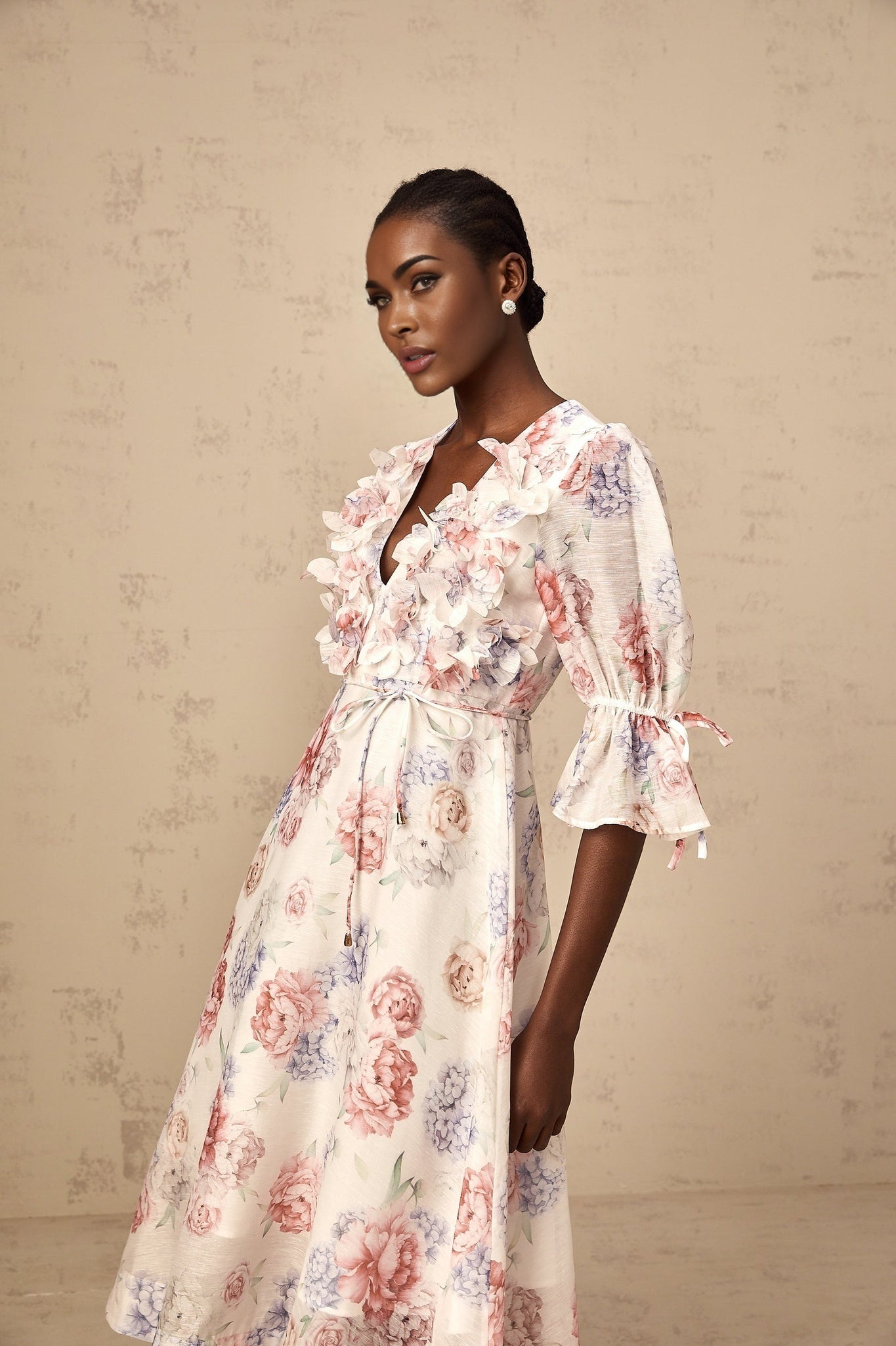 A floral midi dress with a 3d petal design featuring a vibrant multicolored print on a light background