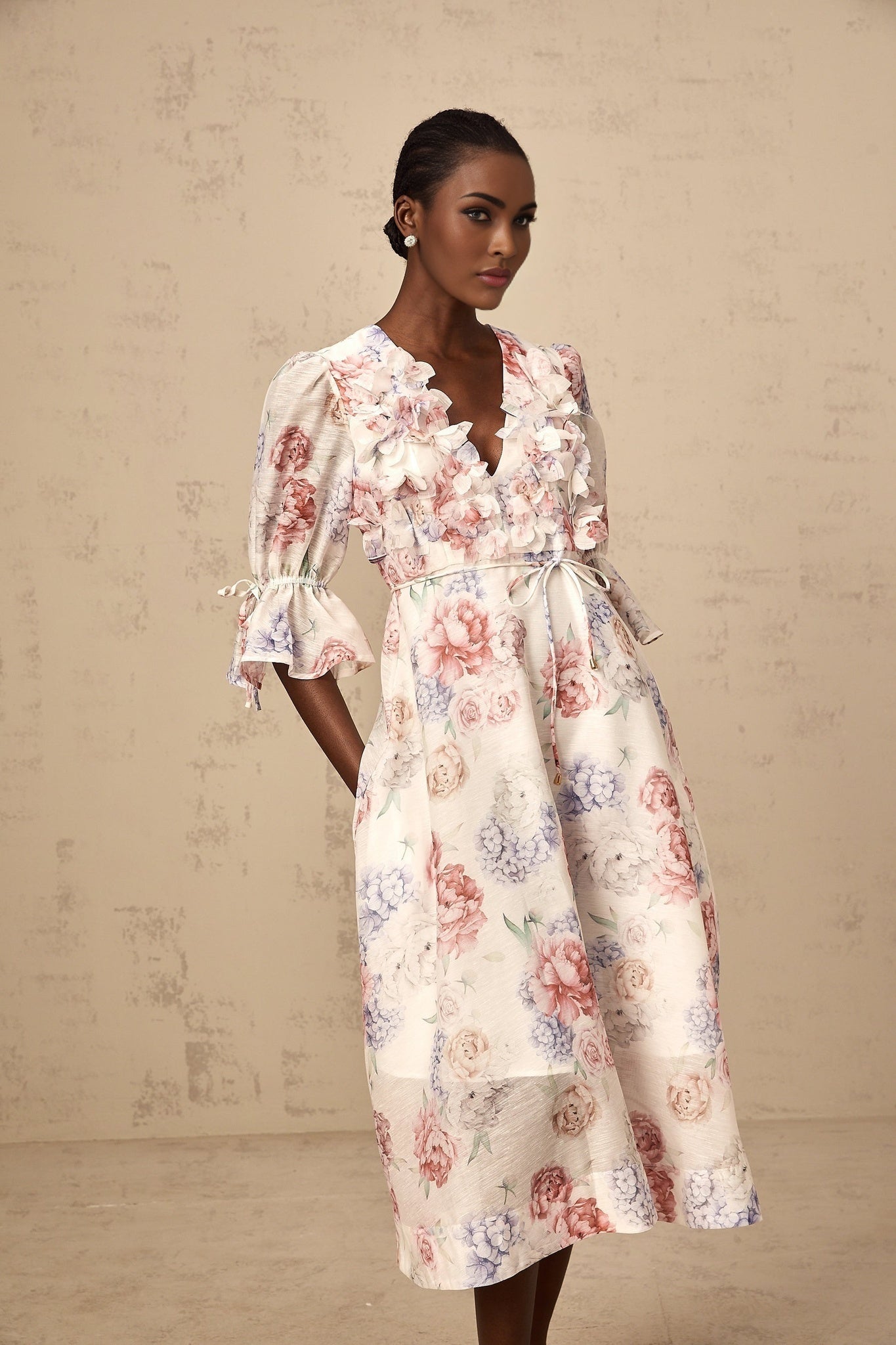 A floral midi dress with a 3d petal print pattern and tea colored background