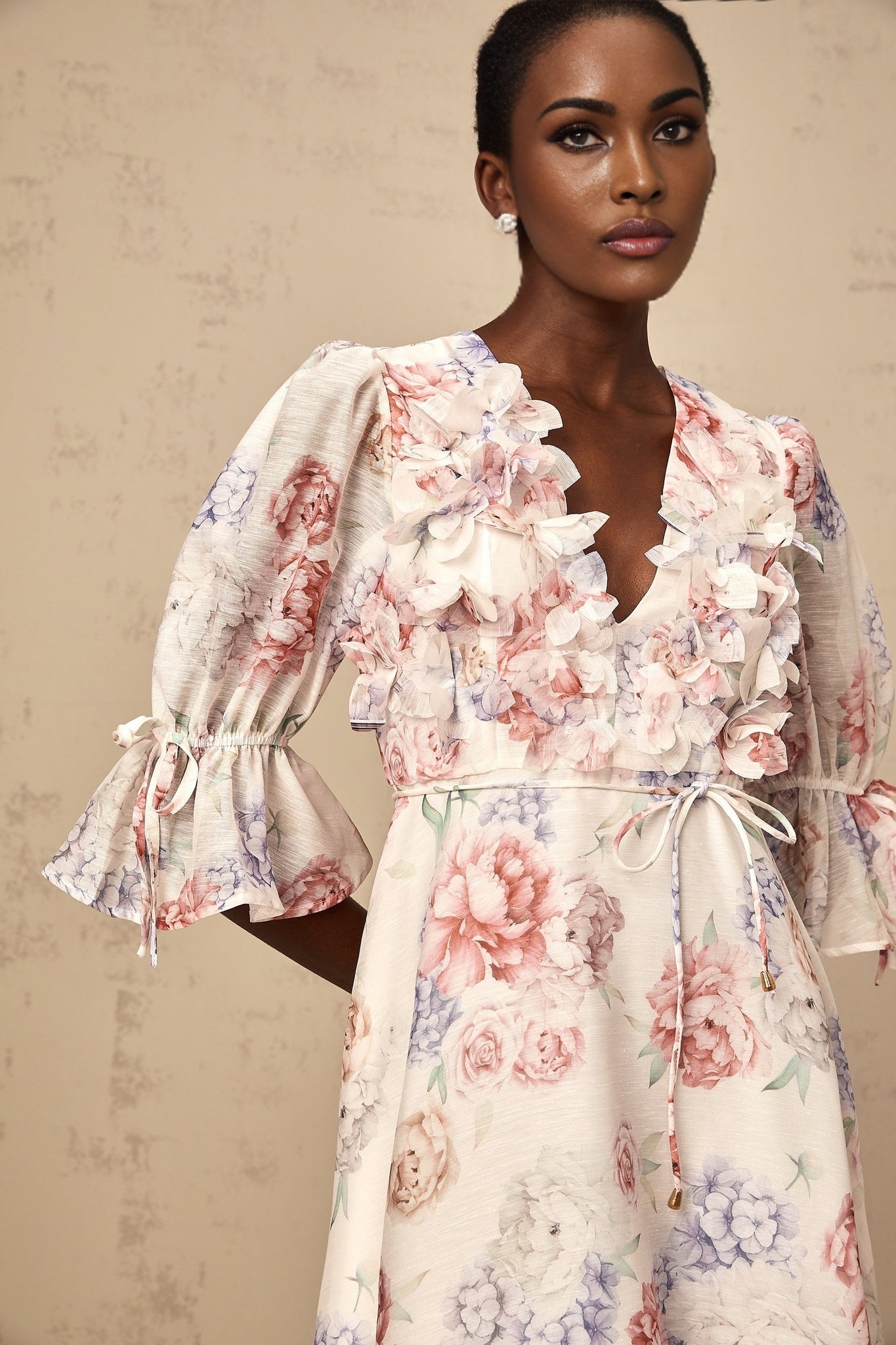 A floral midi dress with a 3D petal print pattern featuring a light background with colorful flower designs