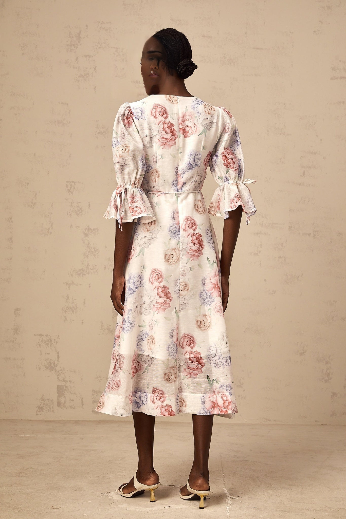 A floral midi dress with a 3d petal print pattern named Tea featuring a vibrant and dimensional floral design on the fabric