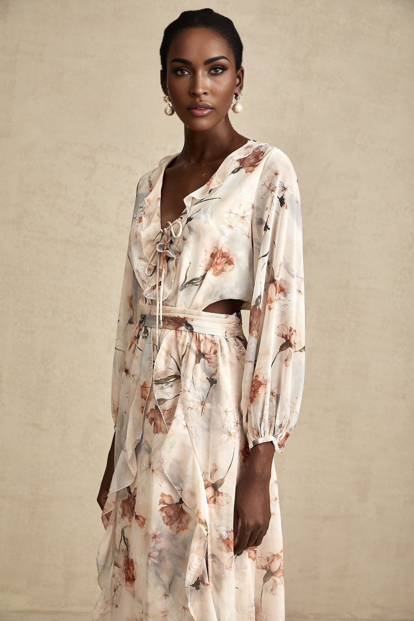 A floral print midi dress with an open waist design featuring a colorful pattern on a light background The dress has a feminine silhouette with a flowing skirt and likely includes details such as short sleeves or straps
