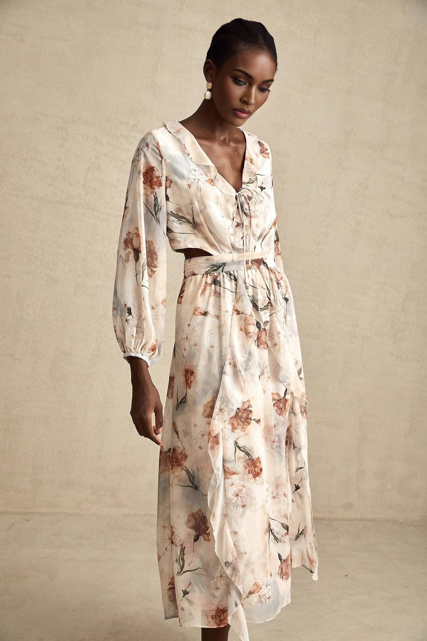 A floral print midi dress with an open waist design featuring a colorful pattern on a light background The dress has a flowing silhouette and appears to be made from a lightweight fabric suitable for warm weather