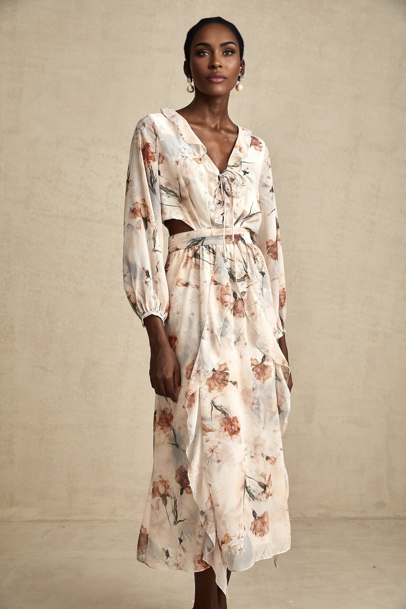 A floral print midi dress with an open waist design featuring a colorful pattern on a light background The dress has a flowing silhouette and appears to be made of lightweight fabric suitable for warmer weather