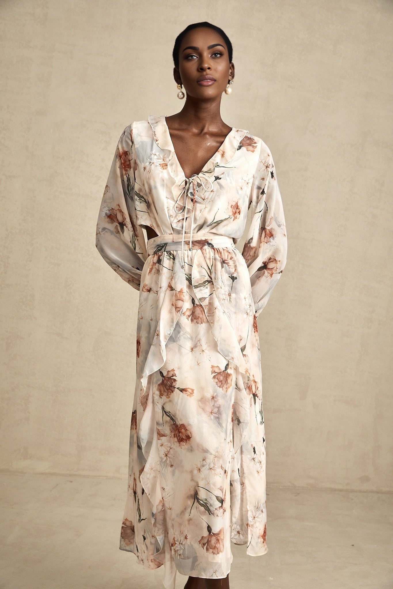 A floral print midi dress with an open waist design featuring a colorful pattern on a light background The dress has a flowing silhouette and hits below the knee