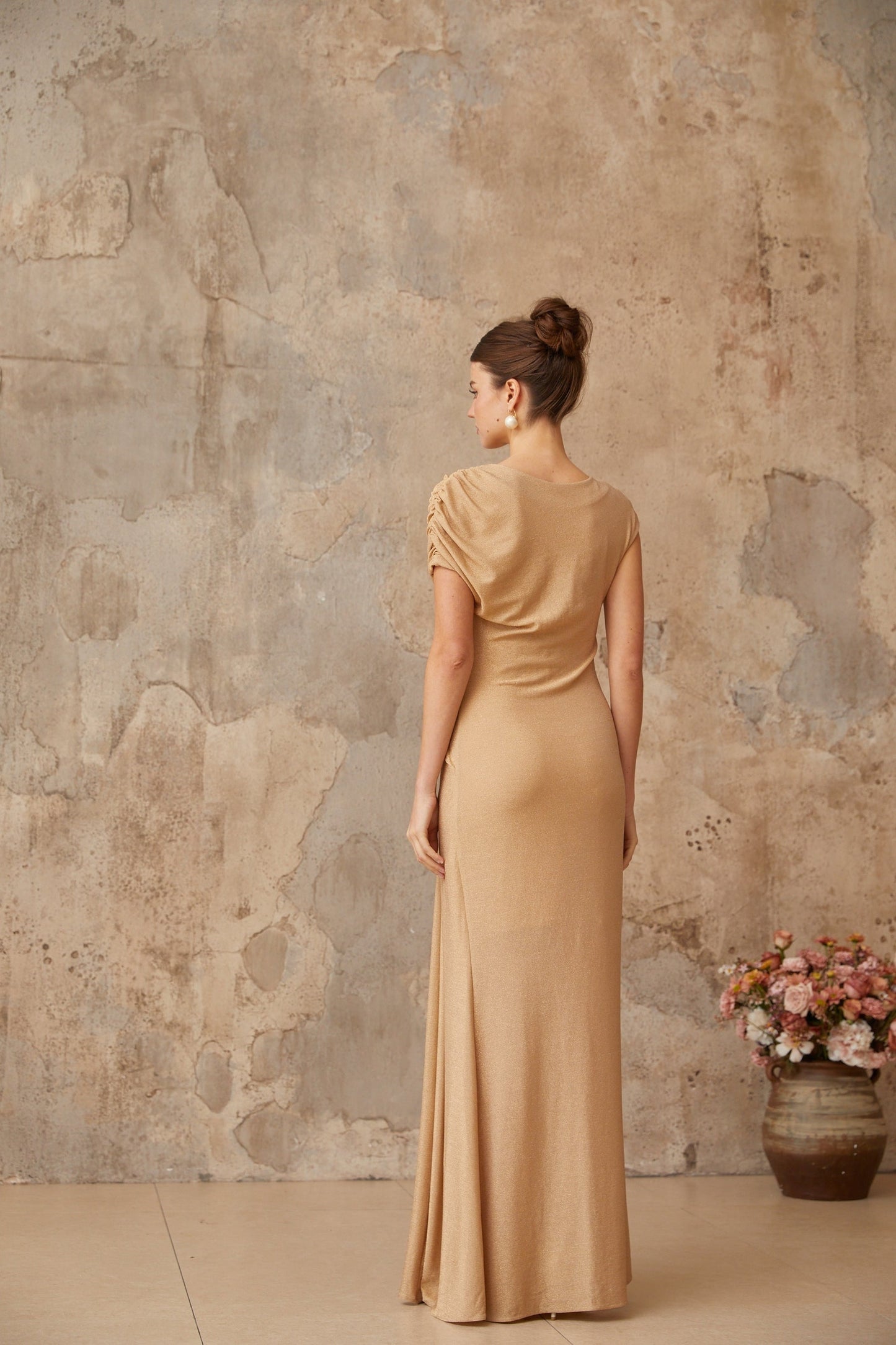 A gold asymmetrical maxi dress with pleated details named Rosalie featuring a long flowing skirt and elegant design