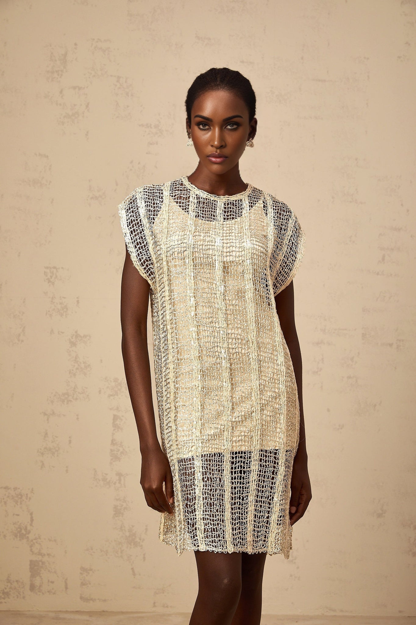 A gold sequined mini dress with cut out details named Solene on a plain background