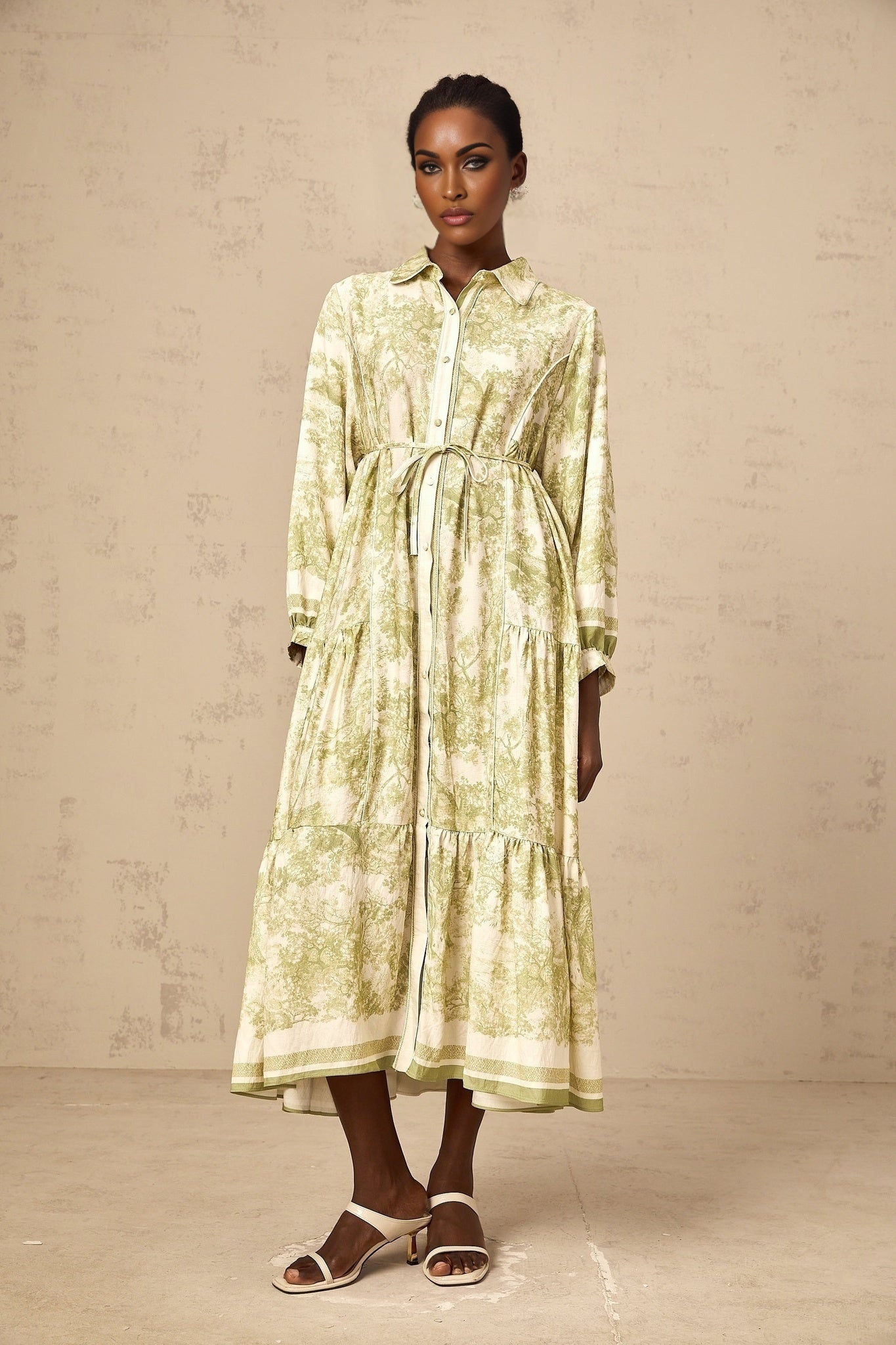 A green midi dress with a graphic print pattern called Adelaide worn by a model standing against a plain background