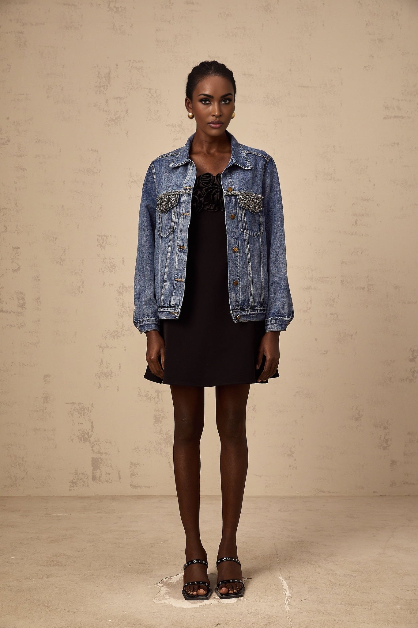 A light blue denim jacket adorned with sparkling rhinestones featuring a classic collar and button front closure