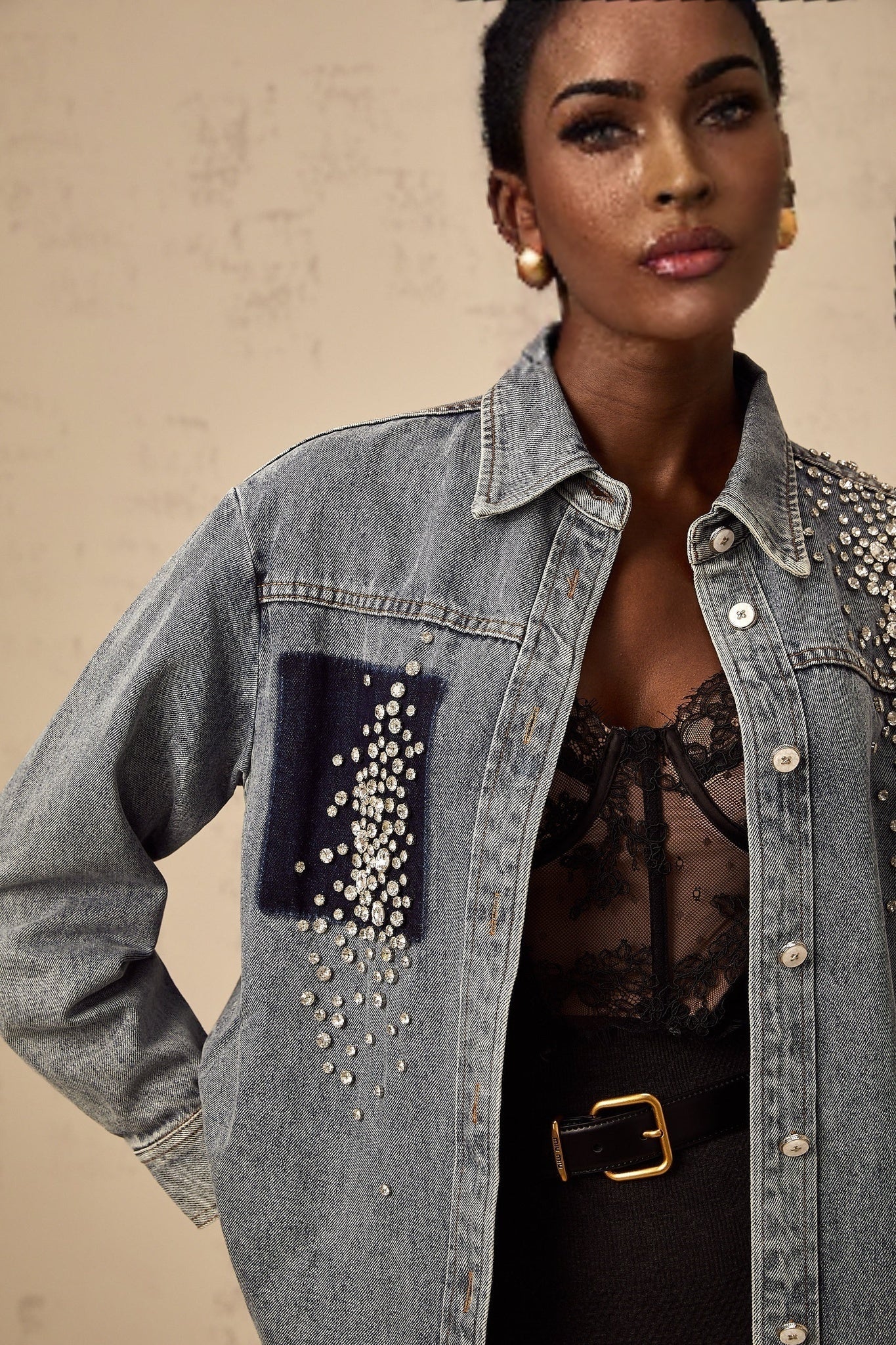 A light blue denim shirt adorned with sparkling rhinestones across the shoulders and chest featuring a classic collar and button front closure