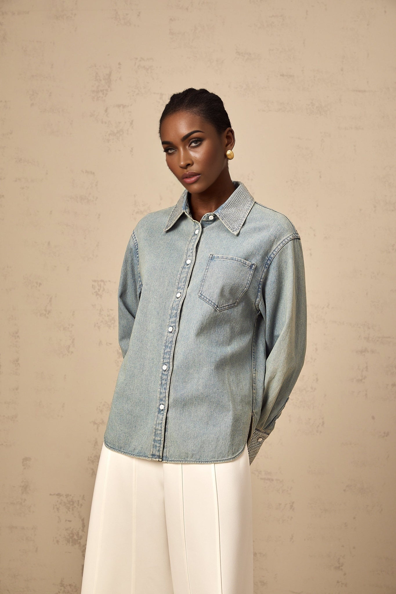 A light blue denim shirt with rhinestone embellishments scattered across the fabric creating a sparkling effect