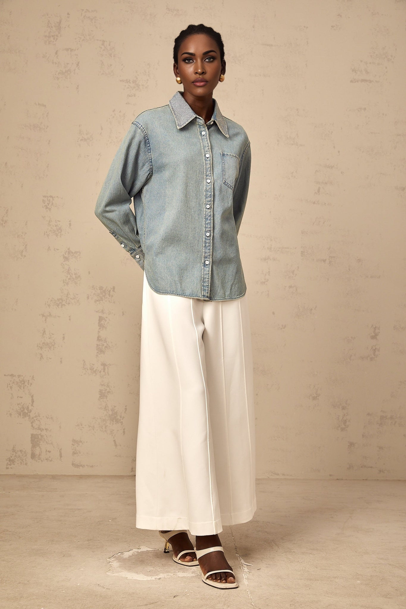 A light blue denim shirt with rhinestone embellishments scattered across the fabric creating a sparkling effect