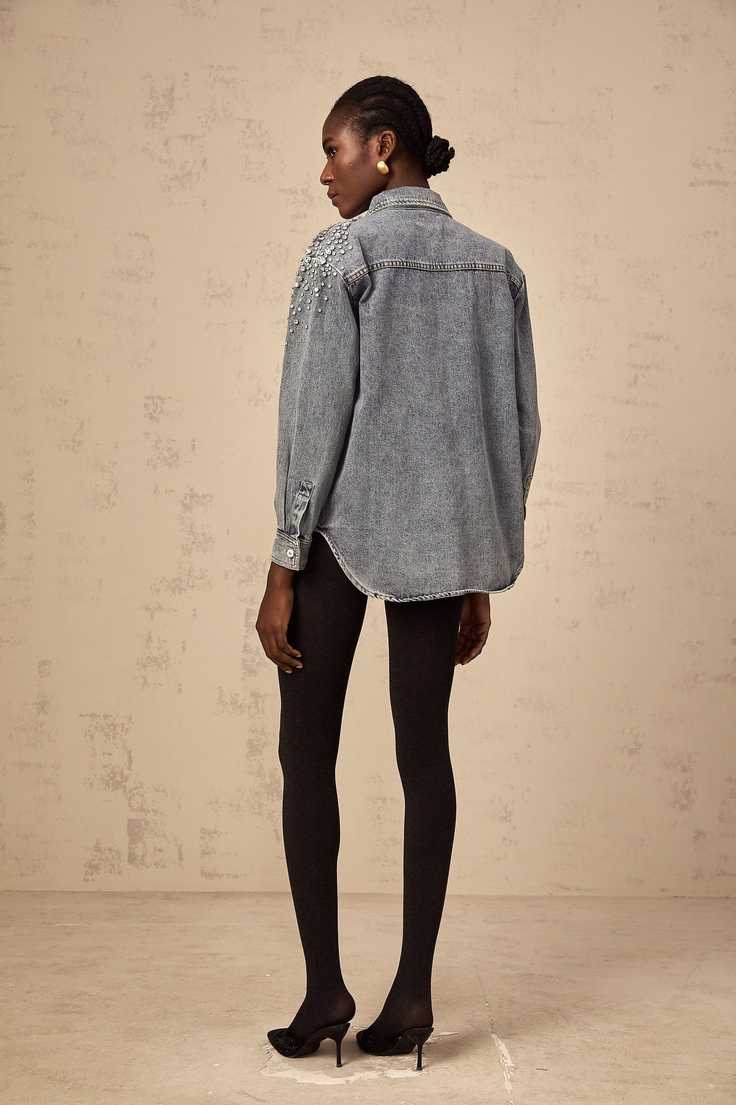A light blue denim shirt with sparkling rhinestone embellishments on the front featuring a western style design and snap button closure