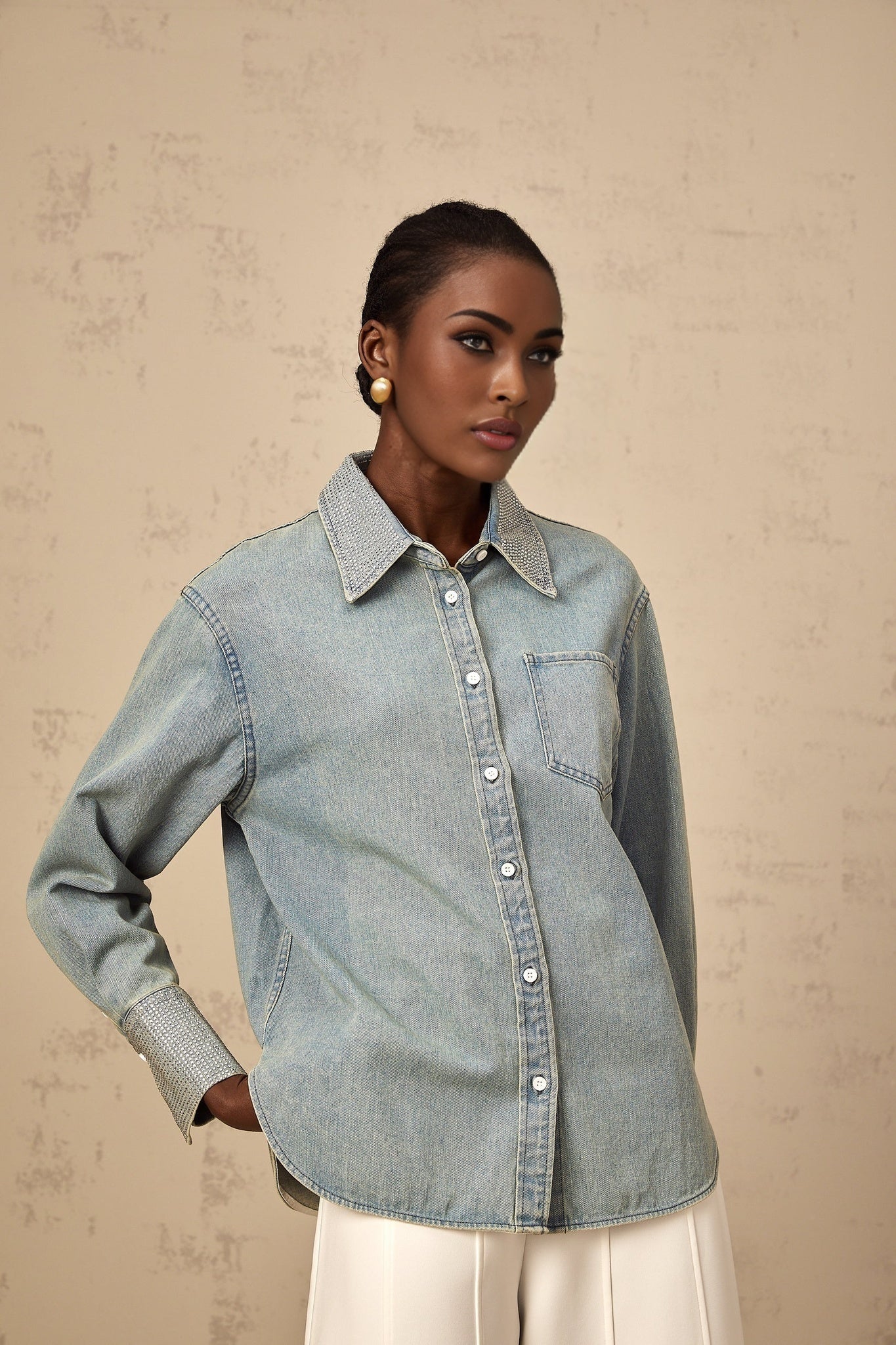 A light blue denim shirt with sparkling rhinestone embellishments scattered across the fabric creating a shimmering effect