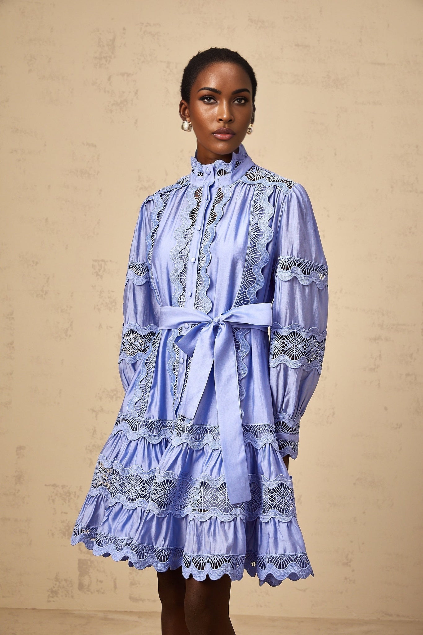 A light blue mini dress with tiered layers and cutout embroidery details featuring a floral motif design short sleeves and a flared skirt