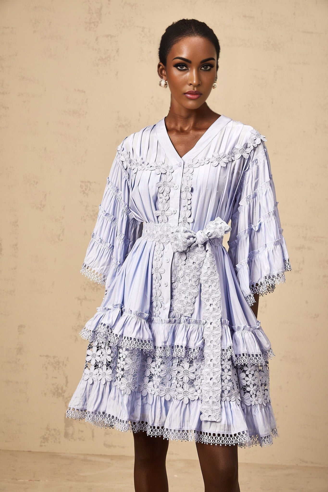 A light blue mini dress with tiered layers and delicate floral embroidery details throughout featuring a short hemline and feminine silhouette