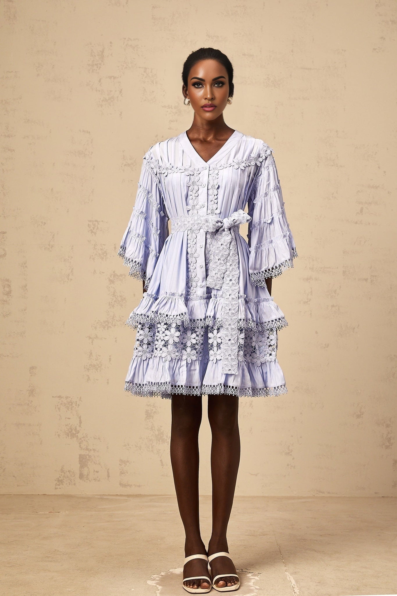 A light blue mini dress with tiered layers and delicate floral embroidery details throughout the fabric