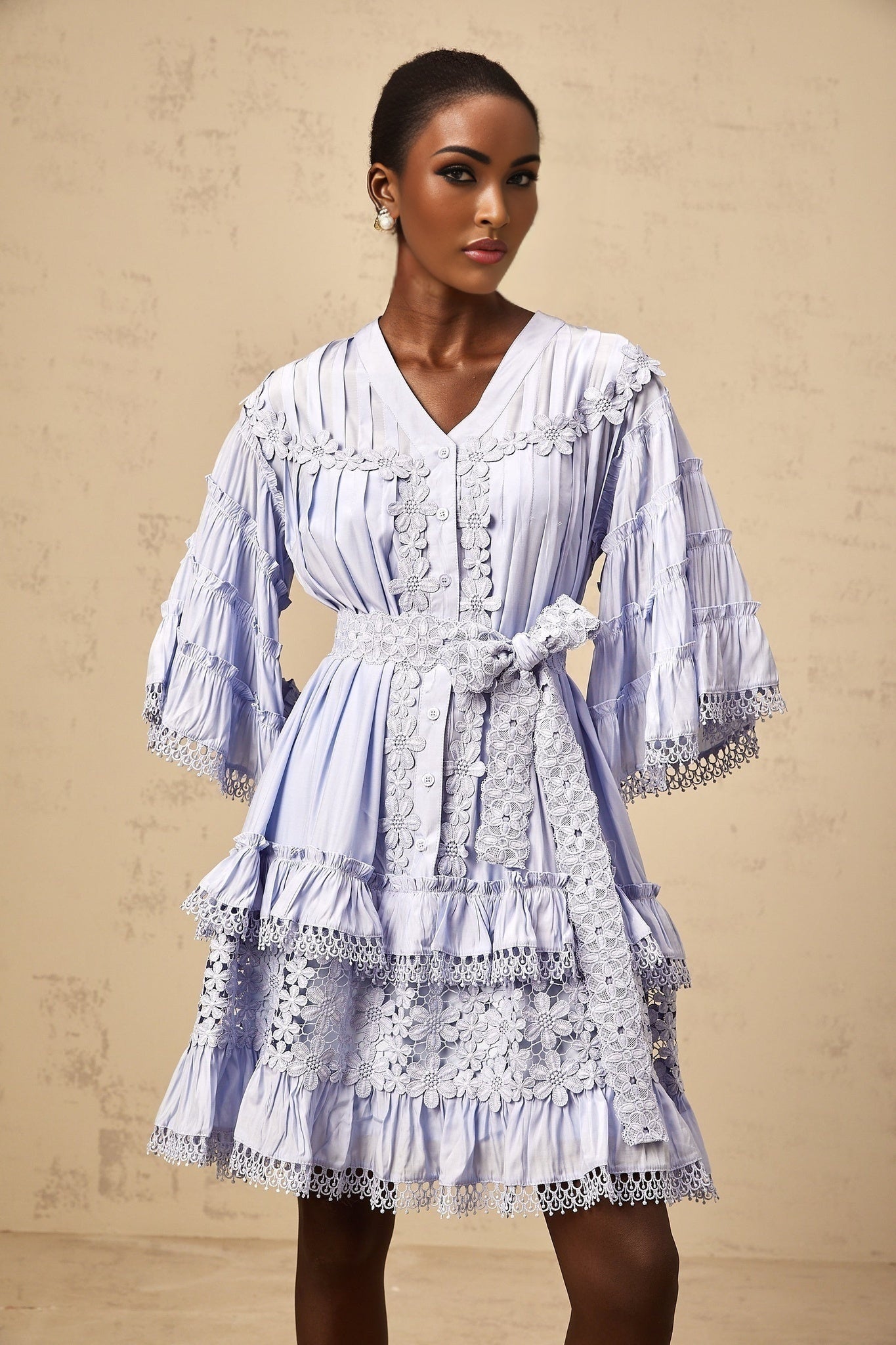 A light blue mini dress with tiered layers and delicate floral embroidery throughout featuring a short hemline and feminine design by Gaelle