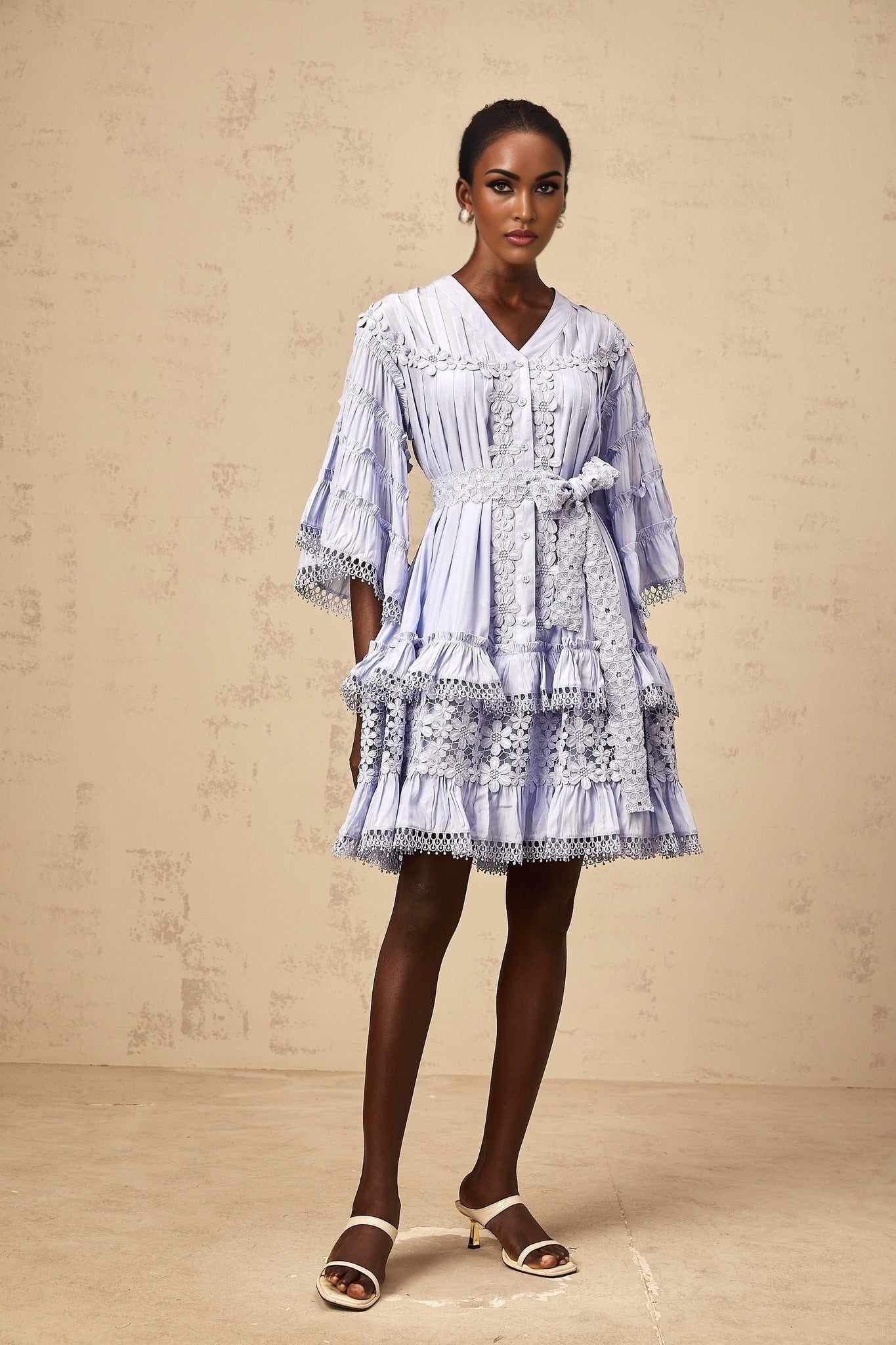 A light blue mini dress with tiered layers featuring delicate floral embroidery details throughout the fabric
