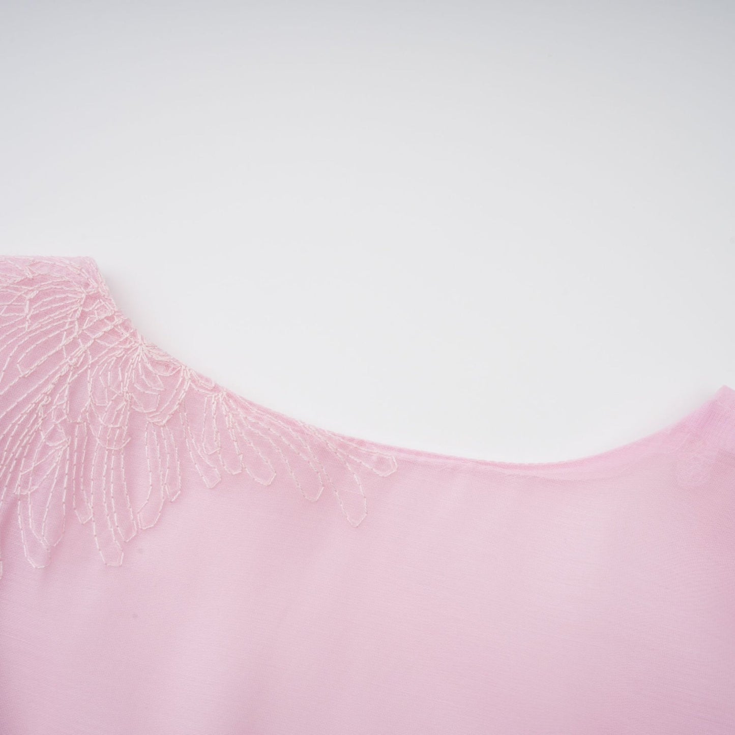A light pink mini dress with floral embroidery and a layered skirt design