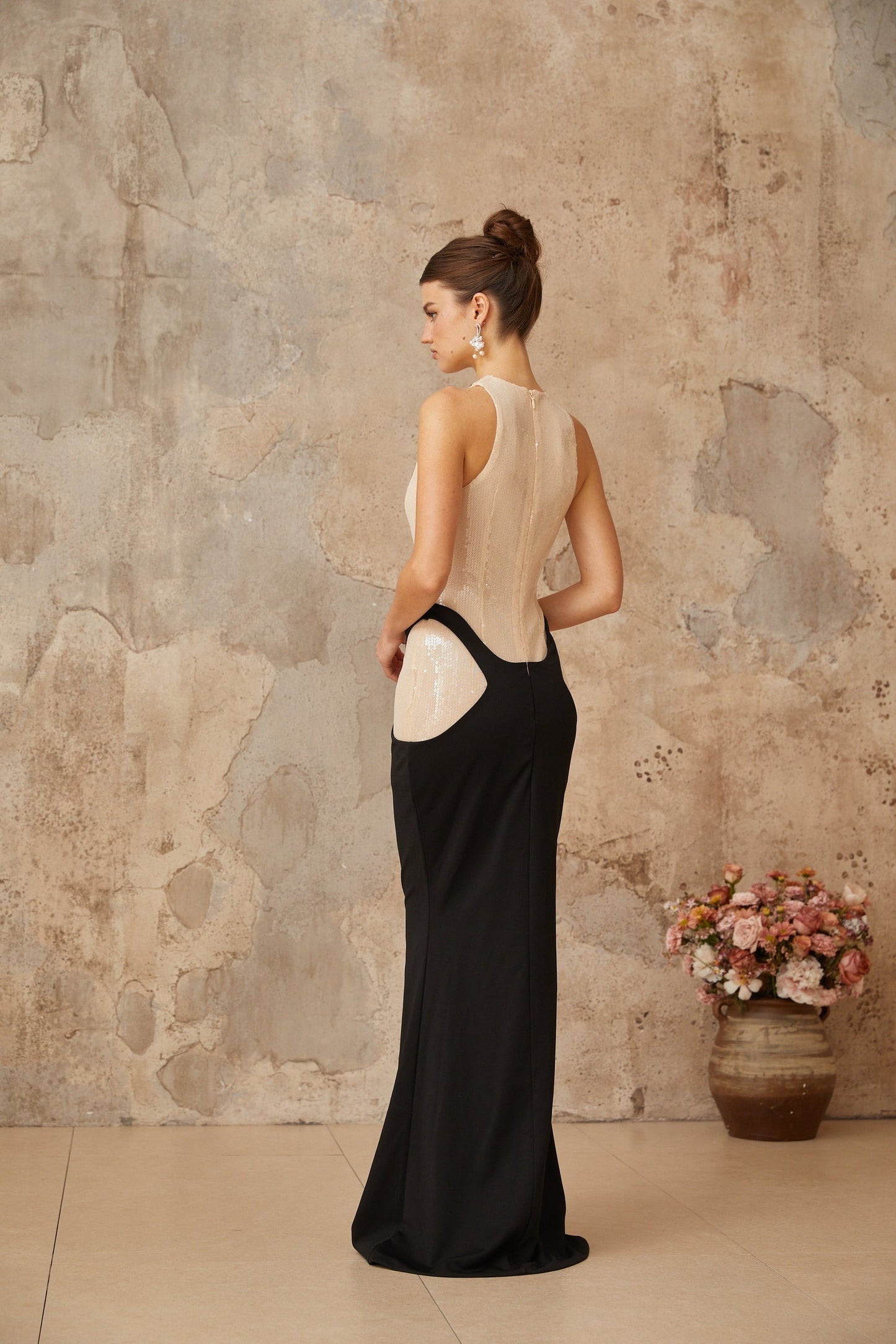 A long black maxi dress with a fitted corset bodice featuring sequin paneling and a flowing skirt