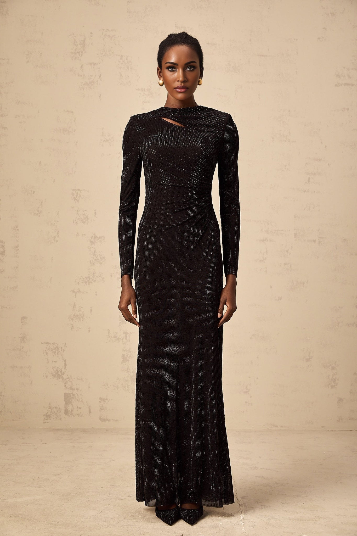 A long black maxi dress with ruched mesh fabric and rhinestone embellishments