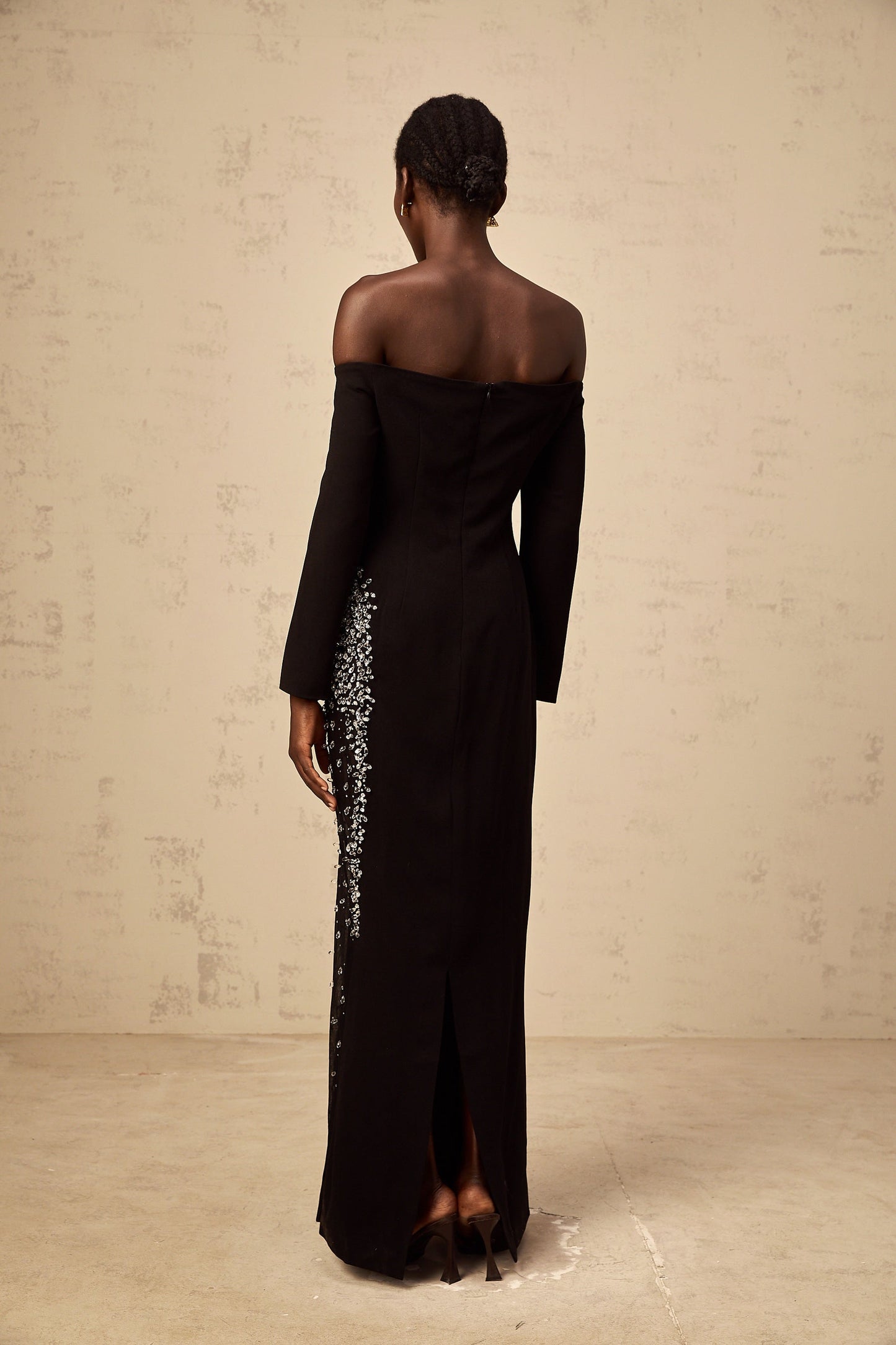 A long black maxi dress with sheer mesh panels and embellished details featuring a fitted silhouette and floor length hem