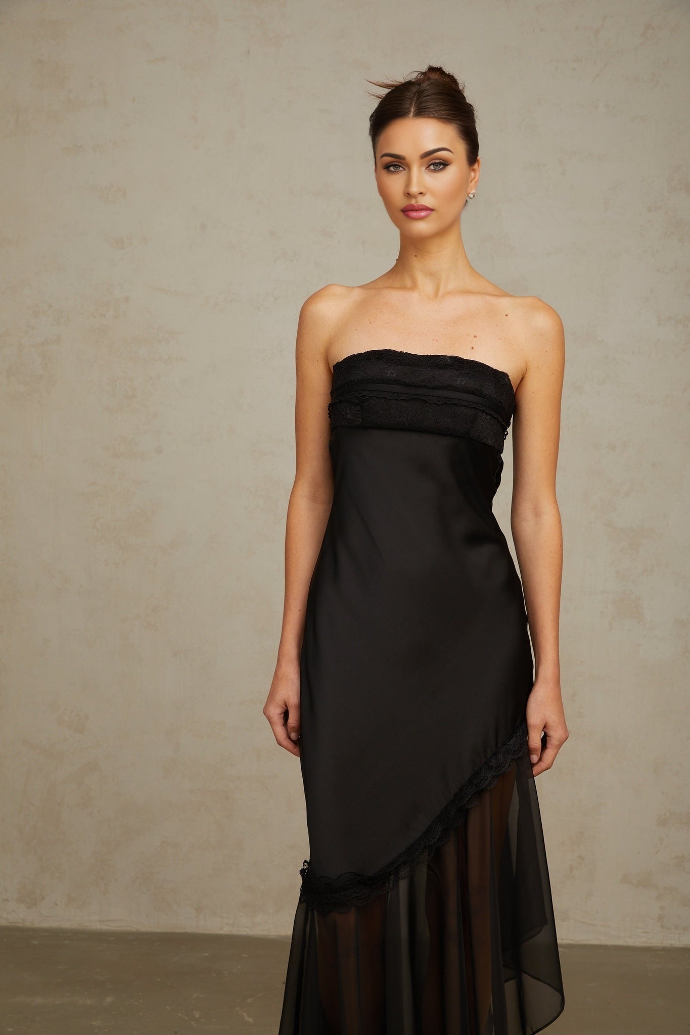 A long black satin maxi dress with sheer tulle panels and a fitted silhouette