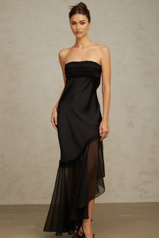 A long black satin maxi dress with sheer tulle panels featuring a fitted bodice and flowing skirt