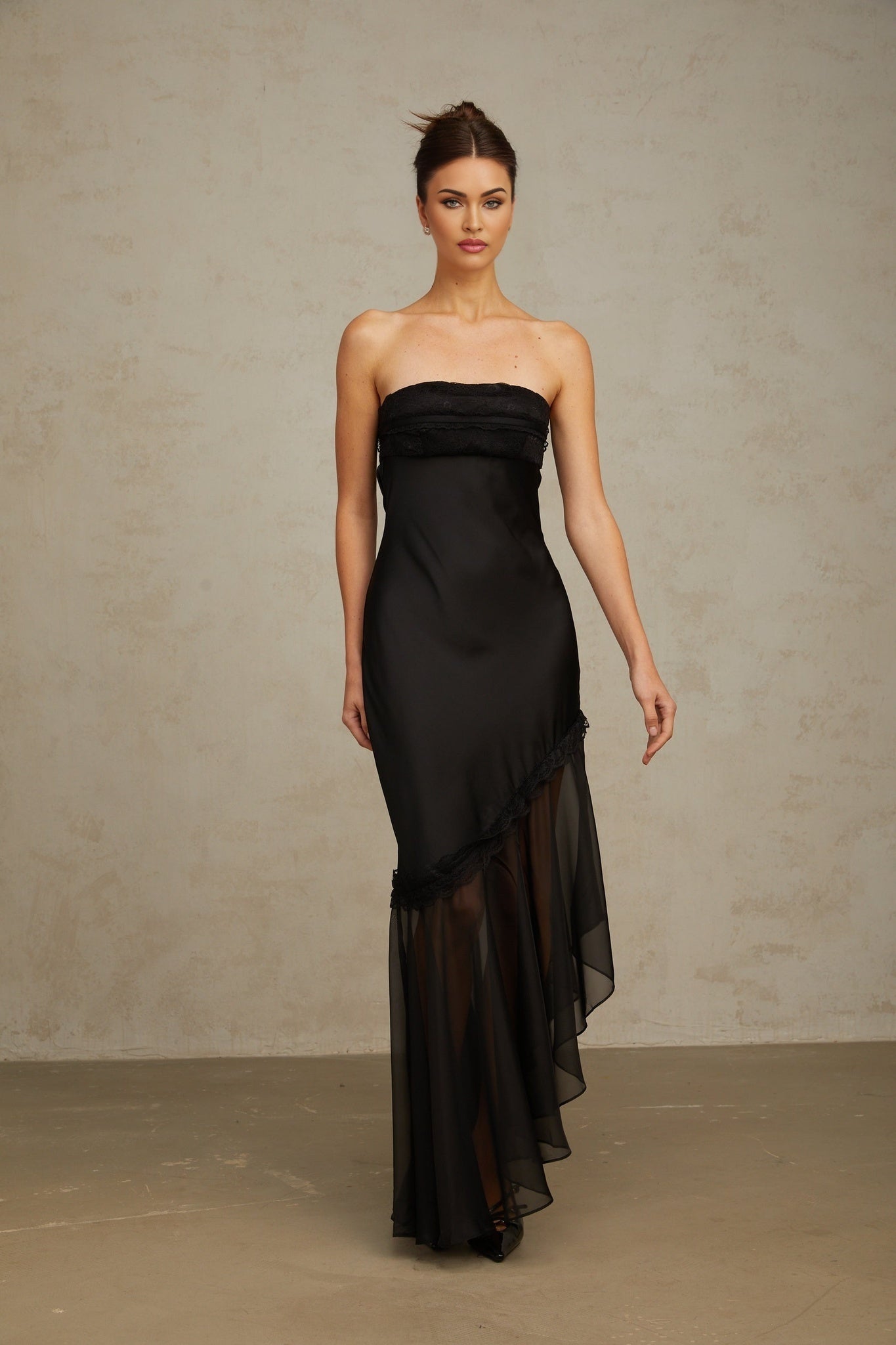A long black satin maxi dress with sheer tulle panels featuring a sleek silhouette and elegant design