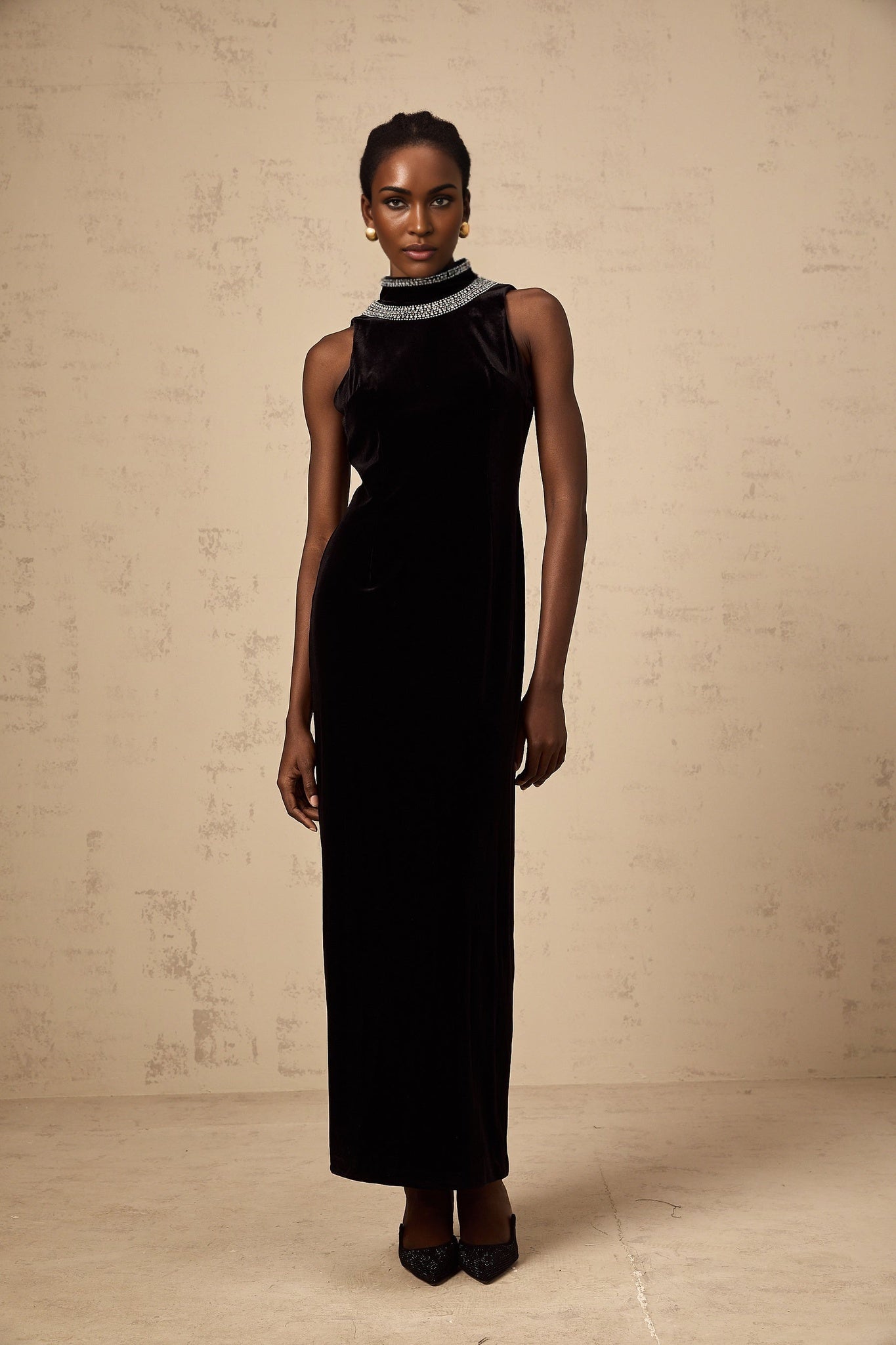 A long black velvet gown with crystal embellishments adorning the dress featuring a fitted silhouette and elegant design