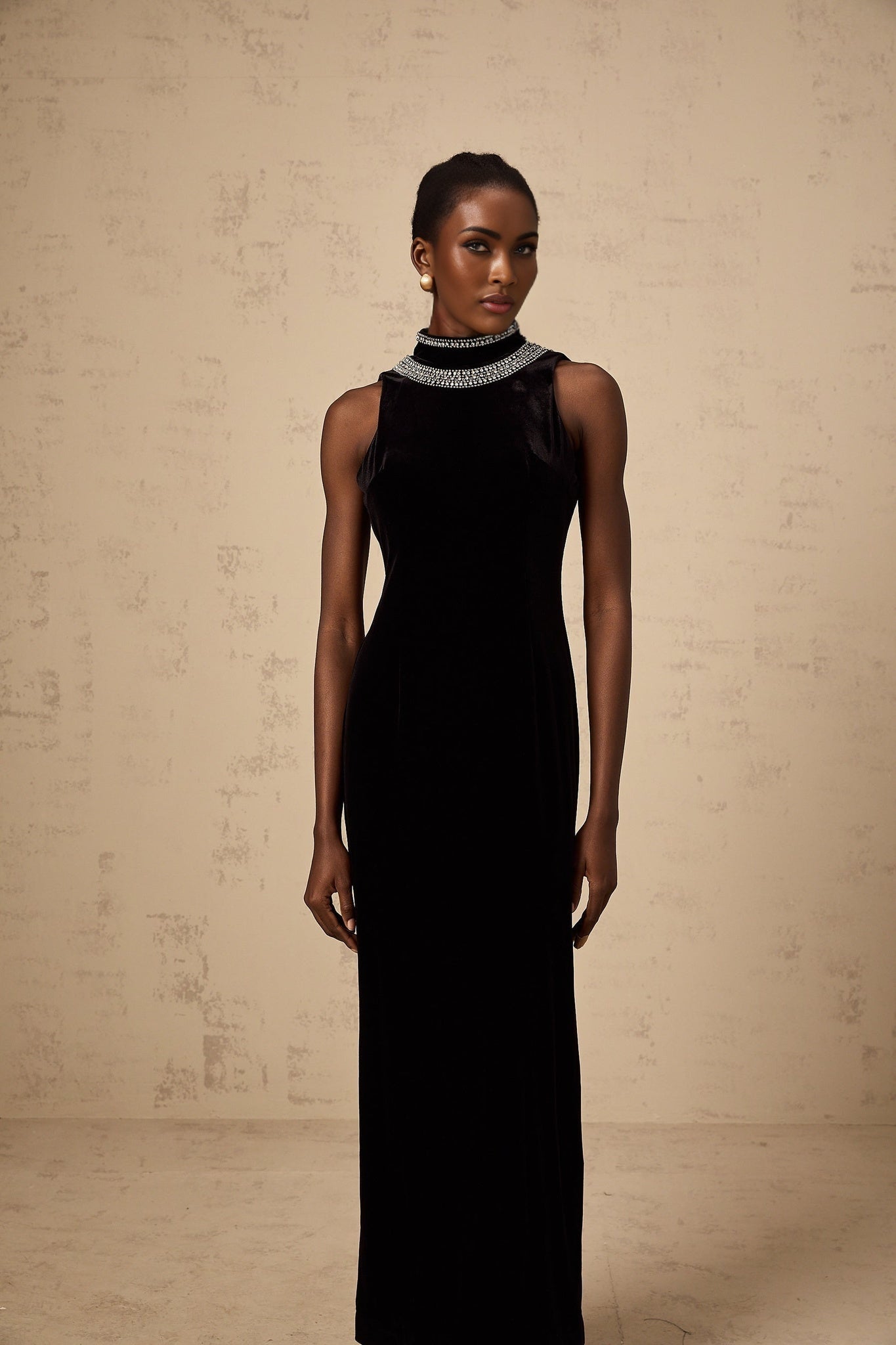 A long black velvet gown with crystal embellishments on a mannequin or model against a plain background