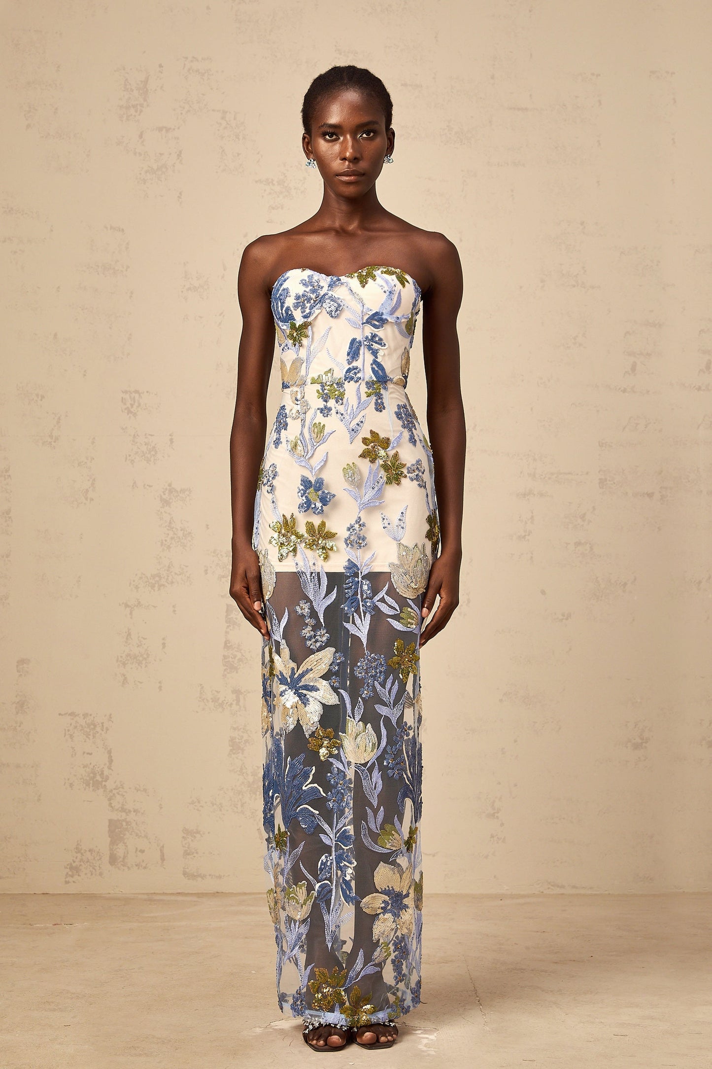 A long blue tulle maxi dress with a corset bodice featuring sequined flower embroidery and a flowy skirt