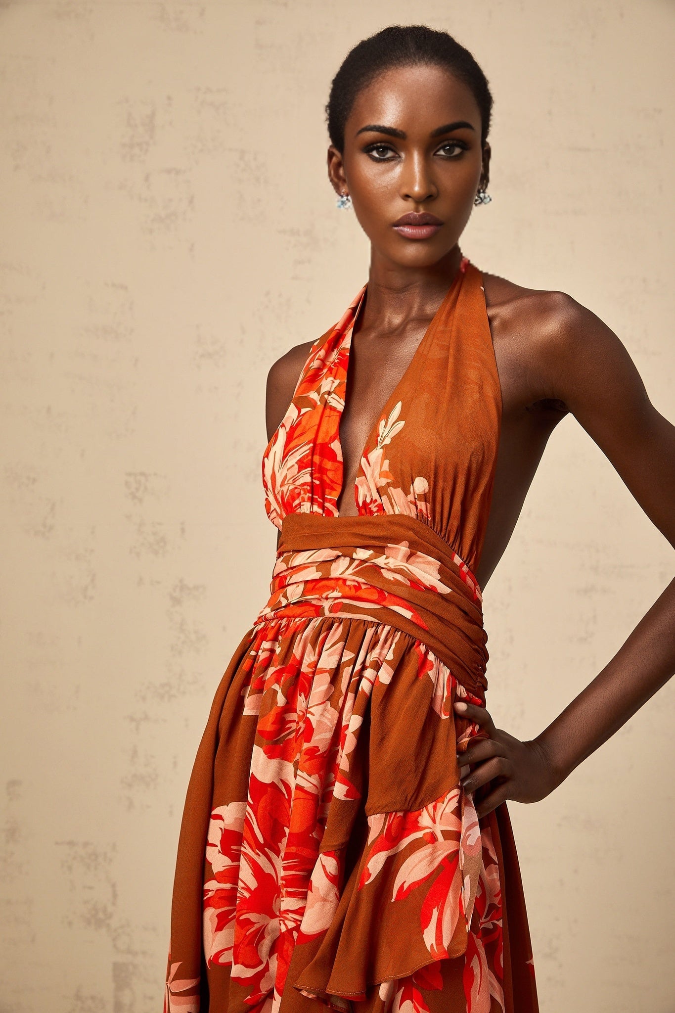 A long brown maxi dress with a floral print pattern featuring an asymmetrical hemline and design elements