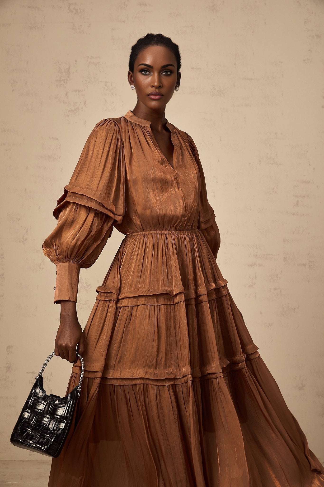 A long brown maxi dress with ruffled trim and tiered layers featuring a feminine flowy silhouette