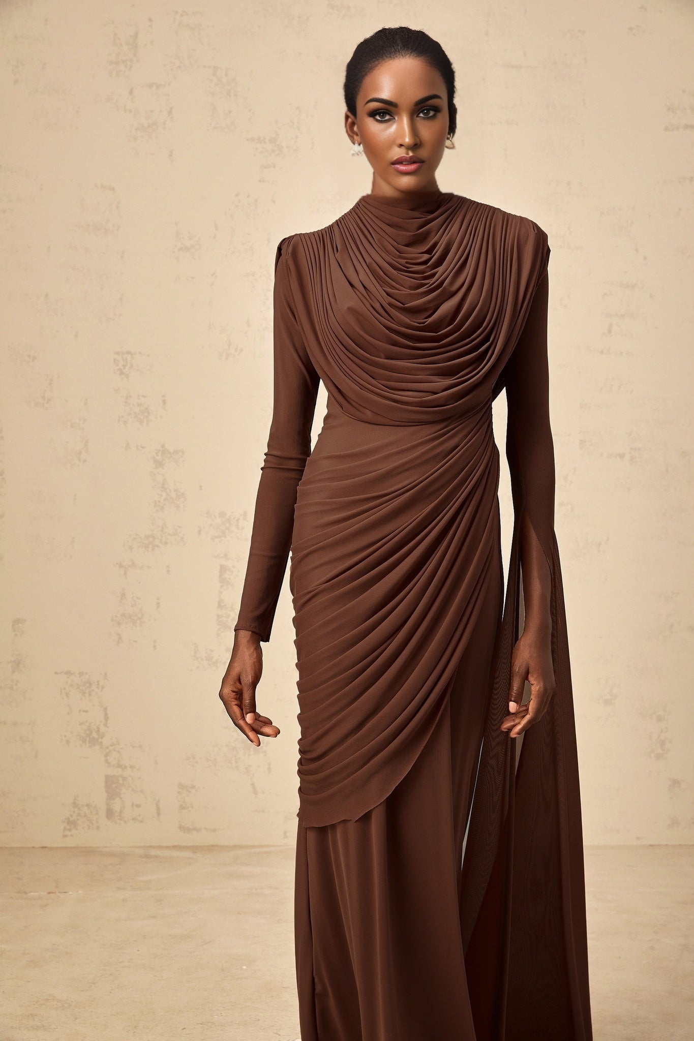 A long brown maxi dress with shirred detailing and draped fabric featuring a flowing silhouette and elegant design