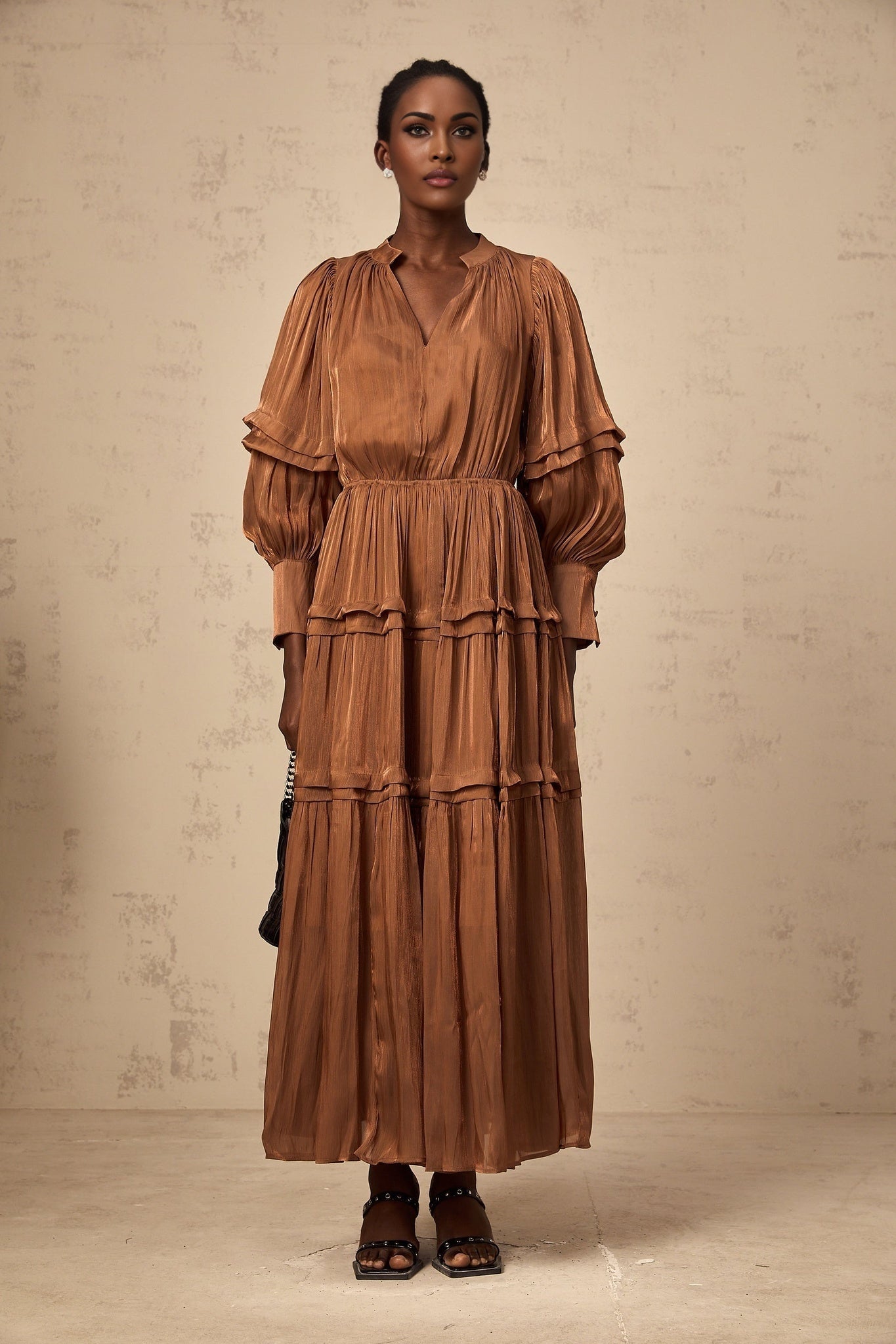 A long brown maxi dress with tiered layers and ruffled trim details