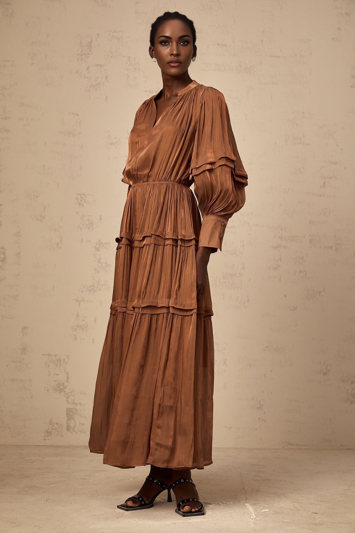 A long brown maxi dress with tiered layers and ruffled trim details