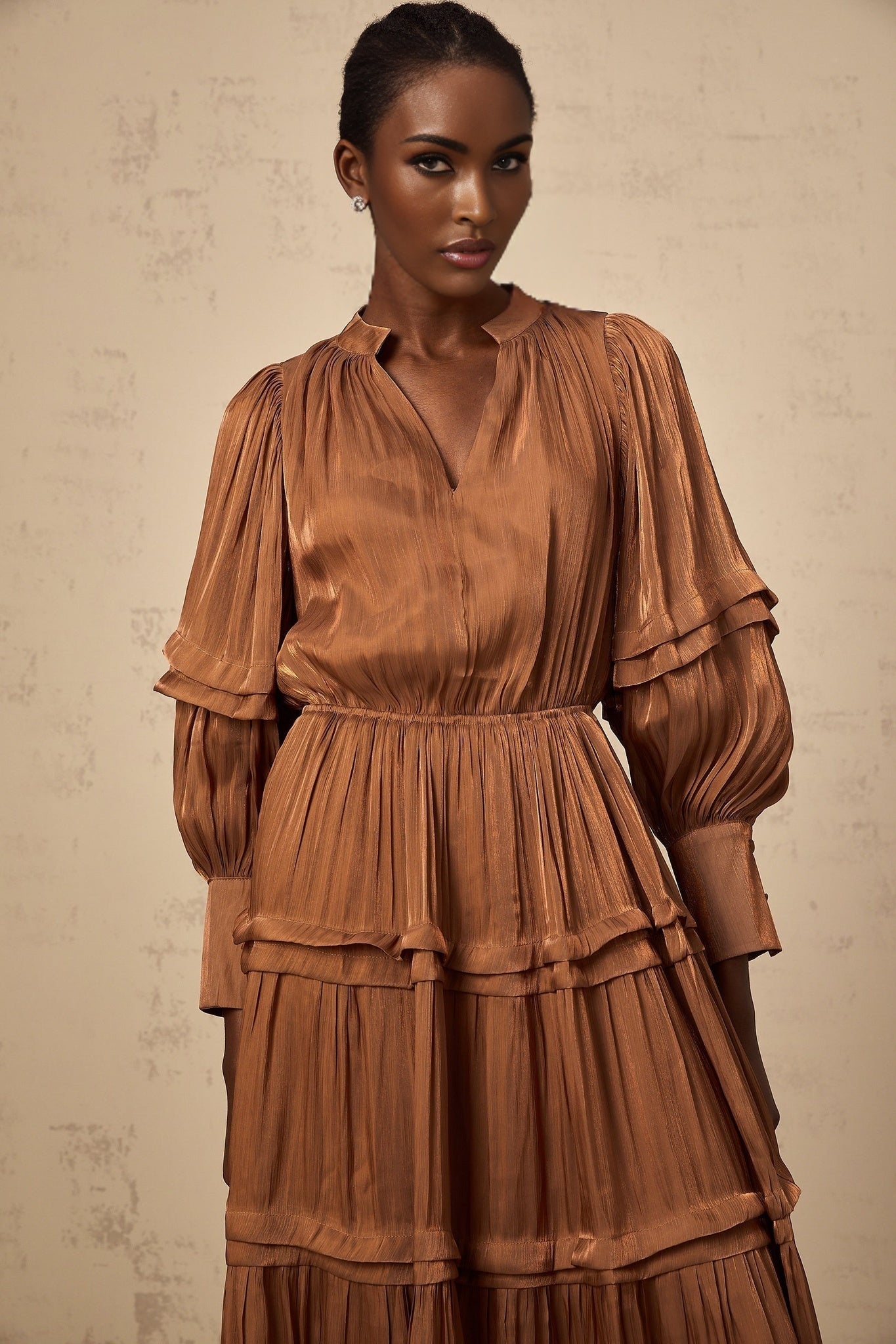 A long brown maxi dress with tiered layers and ruffled trim details