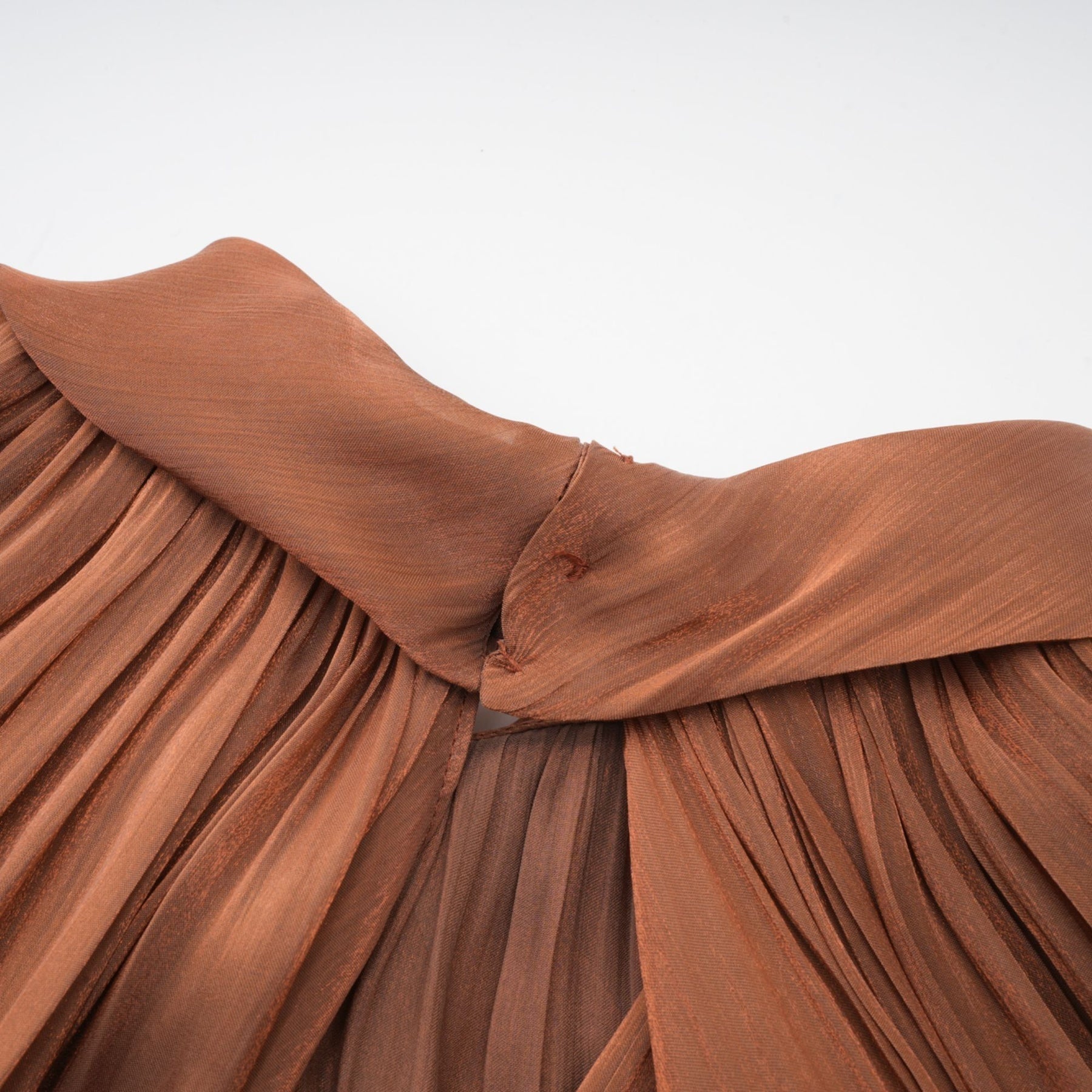 A long brown pleated satin maxi dress with a flowing silhouette and elegant design