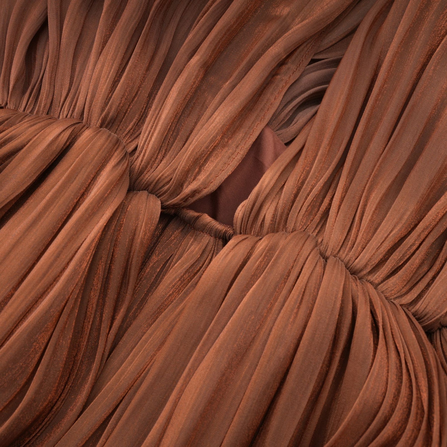 A long brown pleated satin maxi dress with a flowing silhouette and elegant drape