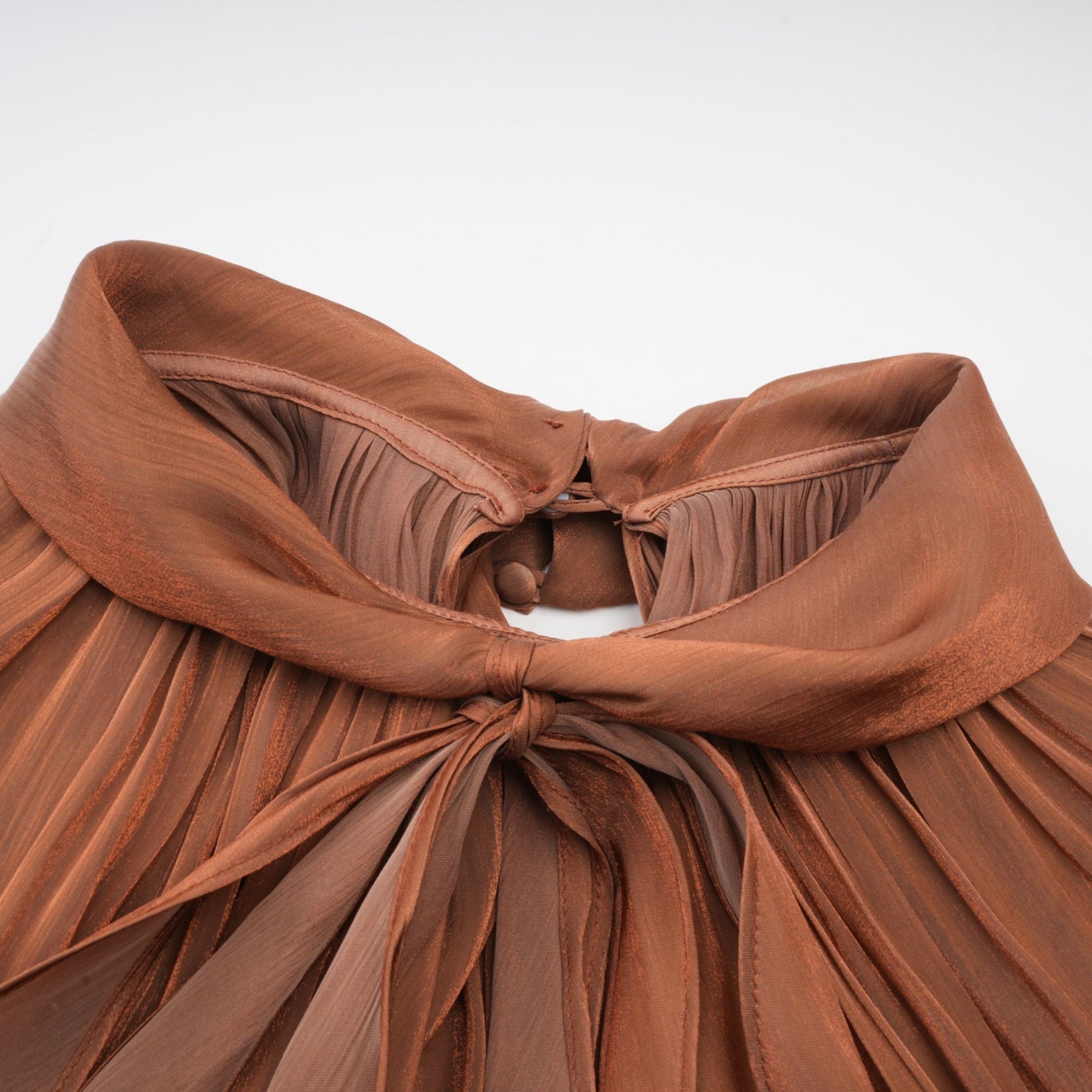 A long brown pleated satin maxi dress with a flowing silhouette and elegant drape