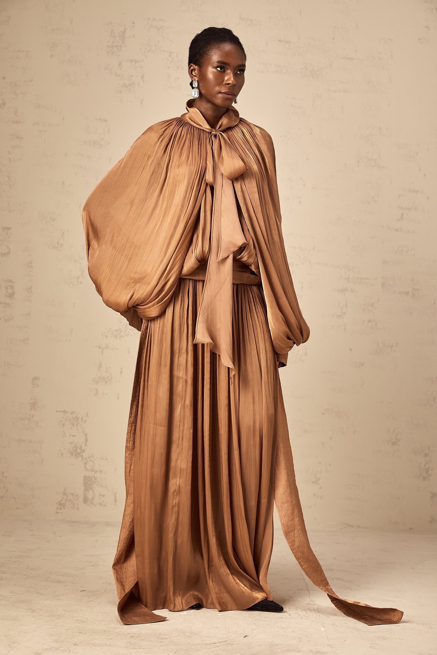 A long brown pleated satin maxi dress with a flowing silhouette named Mila