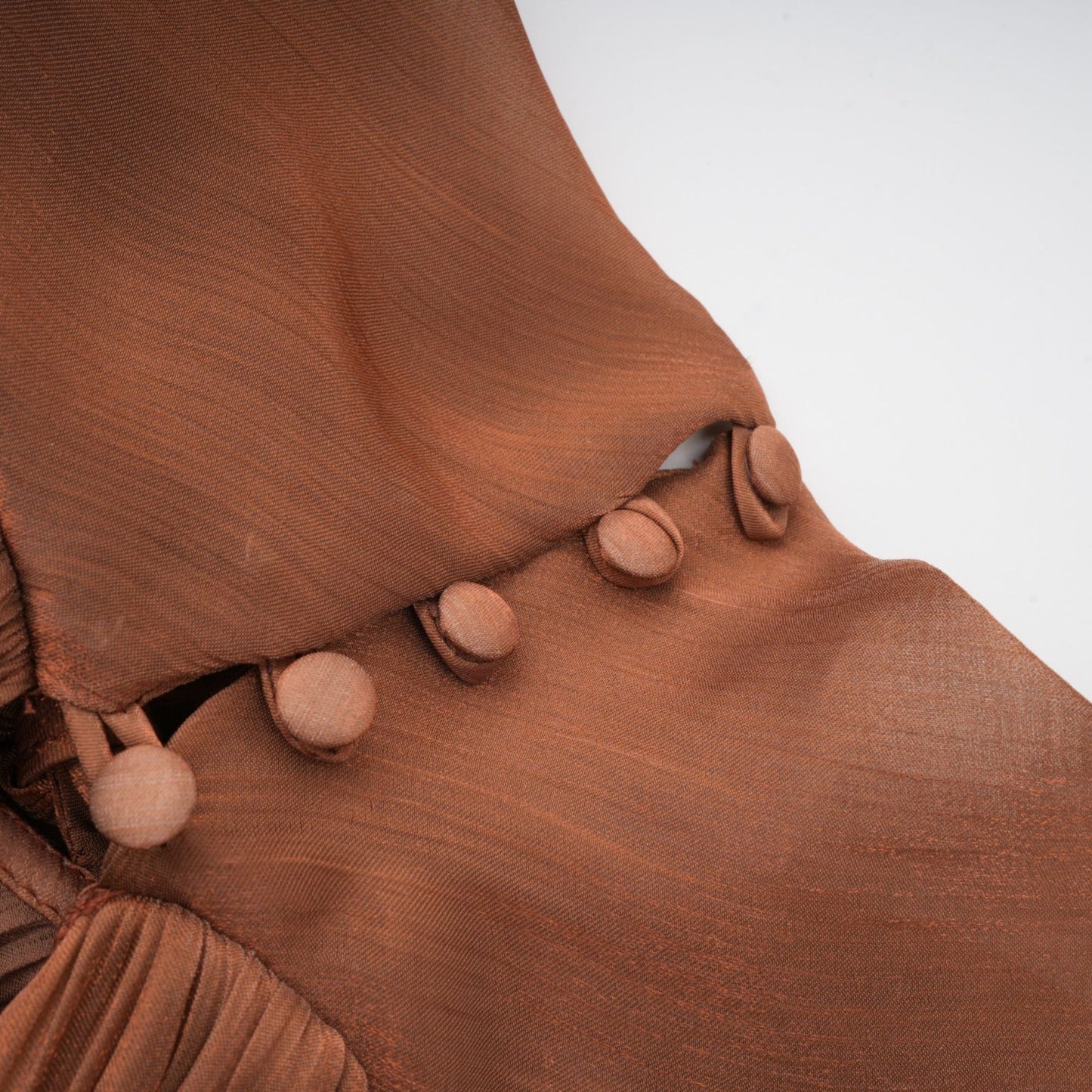 A long brown satin maxi dress with pleated details and a flowing silhouette